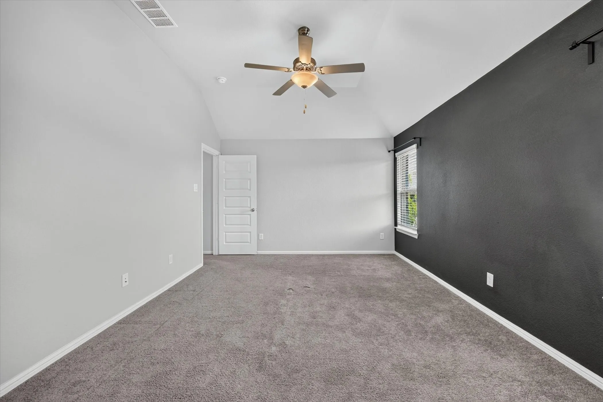 Vaulted ceiling with a ceiling fan, carpeted flooring, and a window with blinds. Carpet has been replaced!