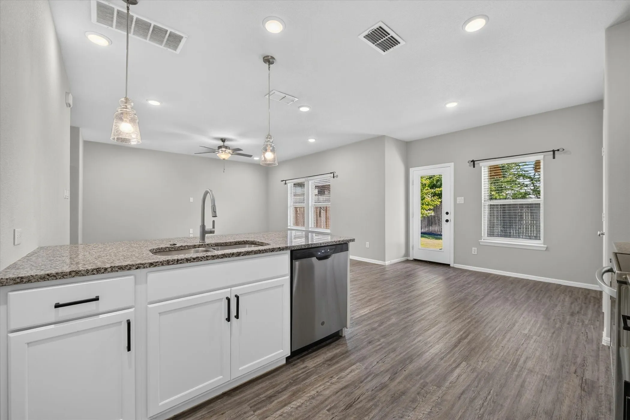 Kitchen island with granite countertop, stainless steel sink, and white cabinetry