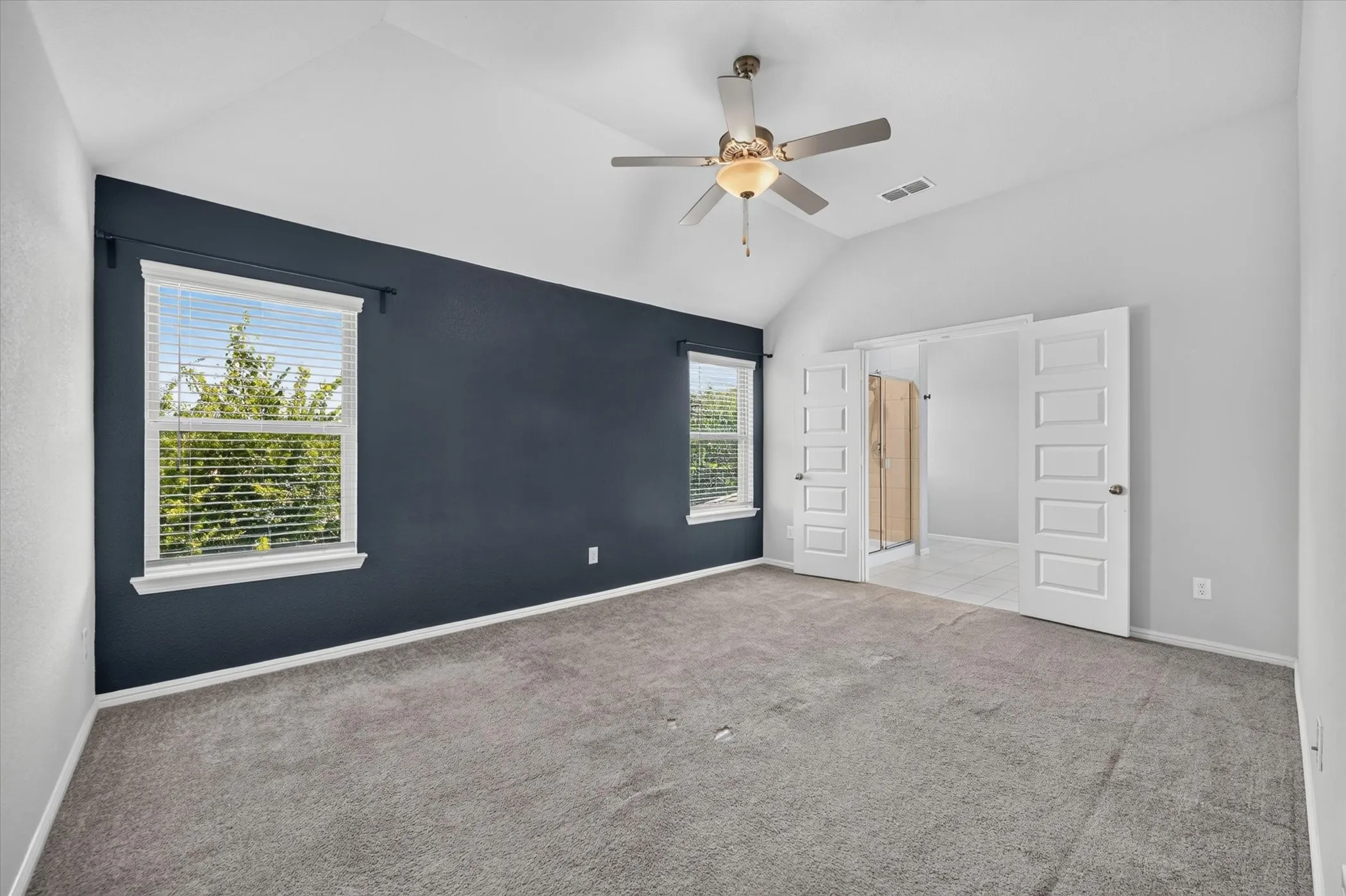 Vaulted ceiling with a ceiling fan, and privacy blinds. Carpet has been replaced!