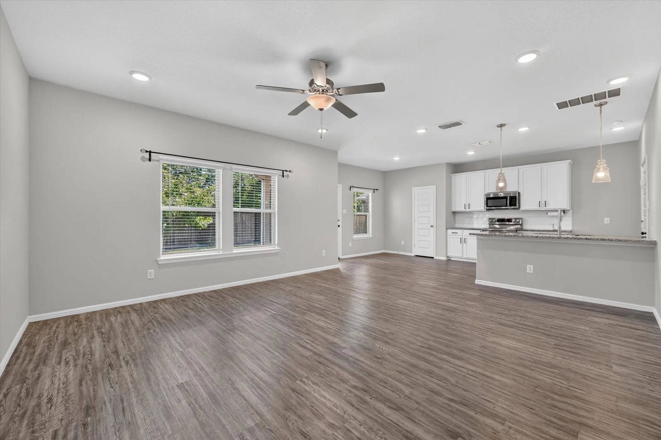 Open-concept living space featuring wood-finish flooring, recessed lighting, and a ceiling fan