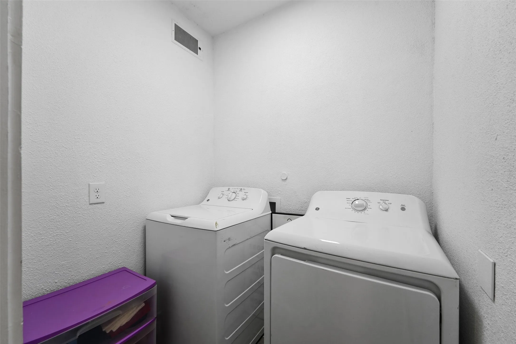 Laundry area with white walls and a ceiling-mounted ventilation register