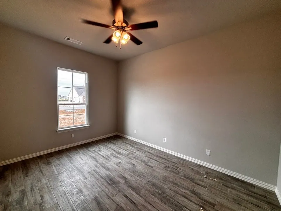 Wood-finish flooring, ceiling fan with integrated lighting, and a double-hung window