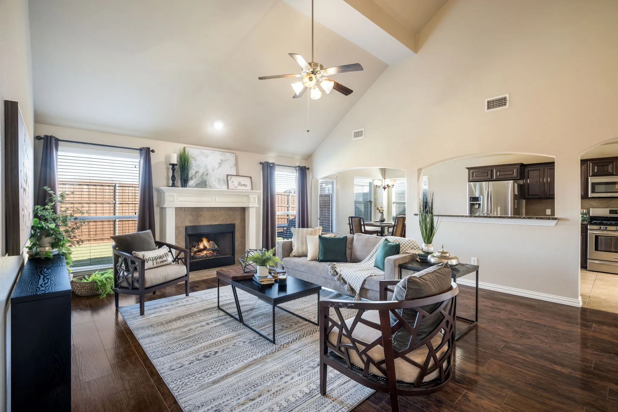 Vaulted ceilings, a stone-surround fireplace with mantel, dark wood-finish flooring, and recessed lighting
