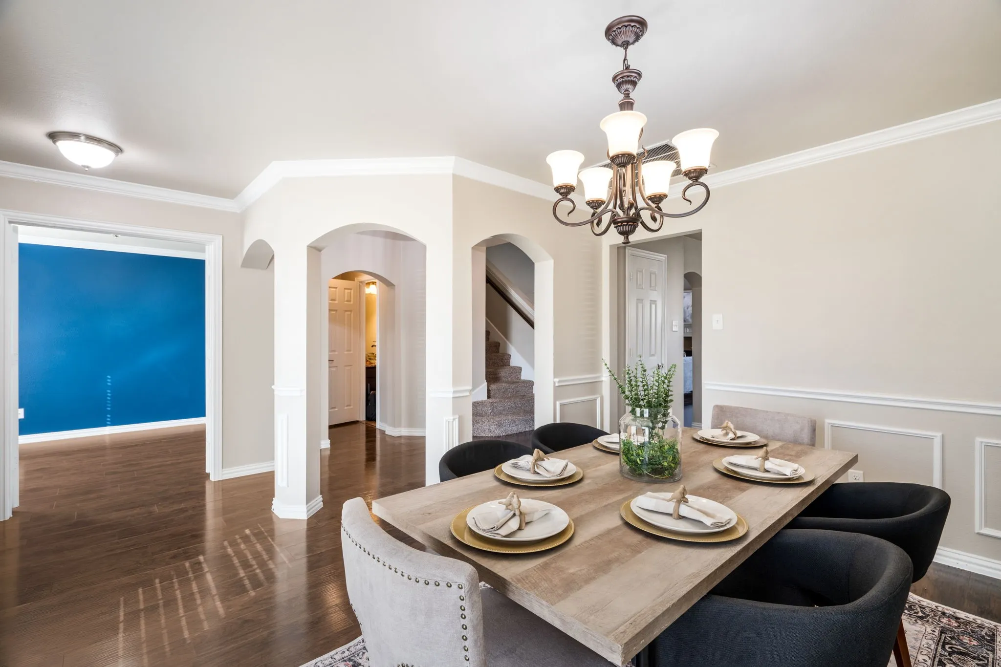 Wood-finish flooring throughout, featuring crown molding, wainscoting, and arched doorways