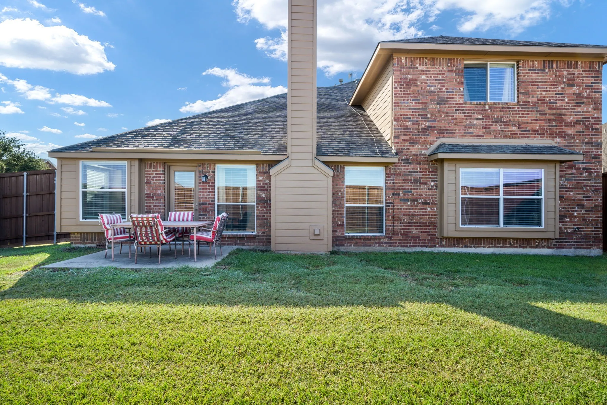 Expansive backyard with a manicured lawn, concrete patio, and privacy fencing