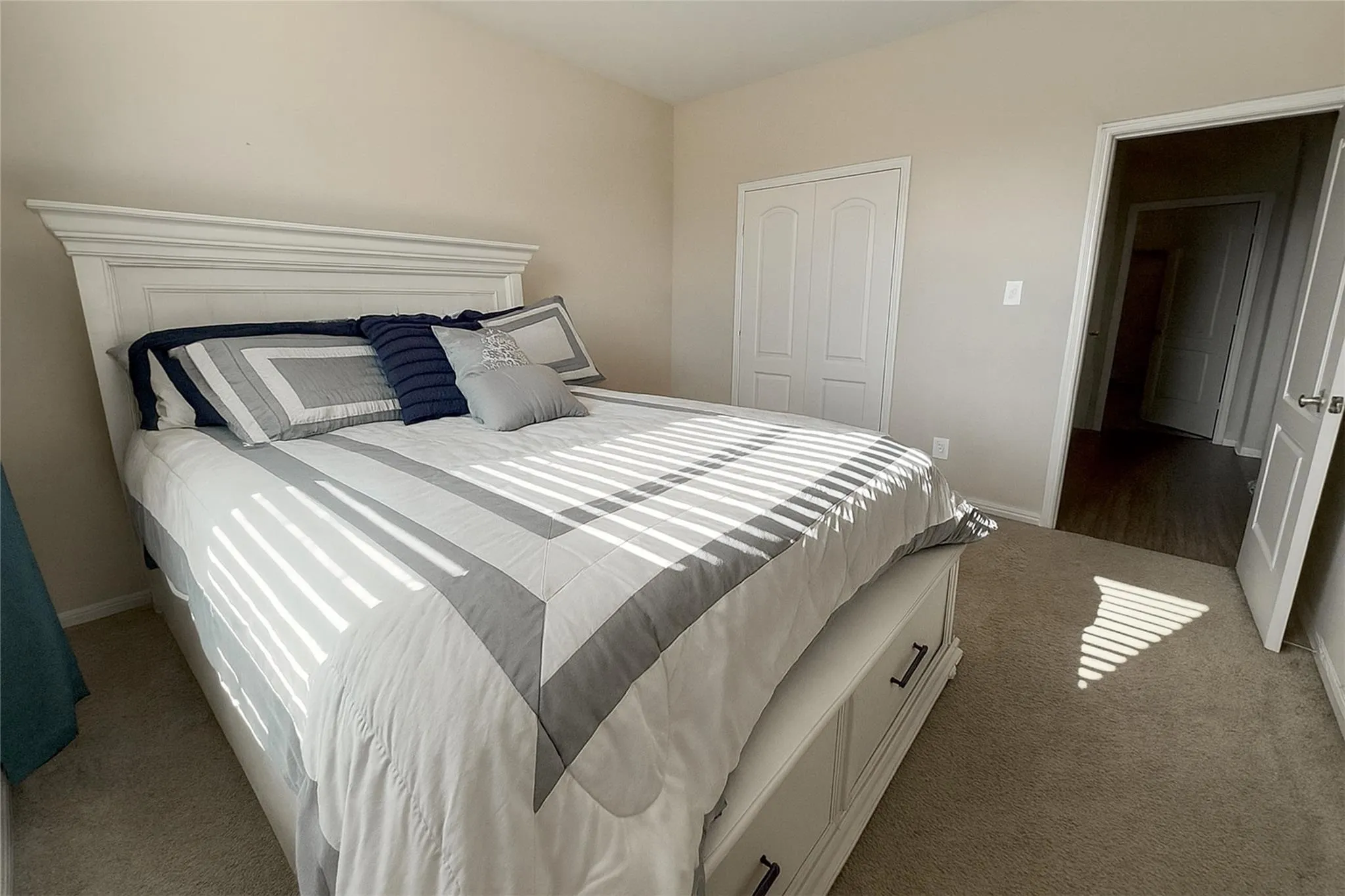 Neutral wall color, carpeted flooring, bi-fold closet doors, white trim, and a hollow core door leading to another area