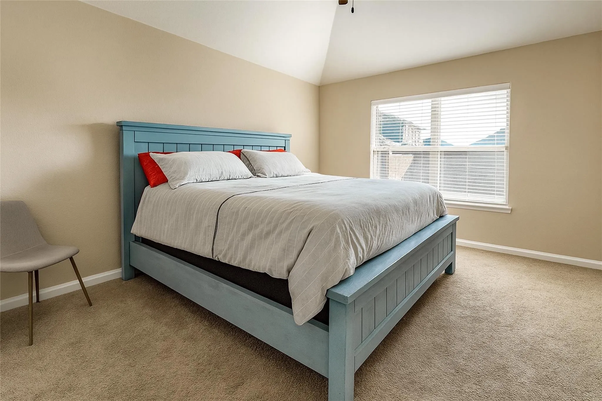 Carpeted room featuring a vaulted ceiling, a window with blinds, and neutral wall tones
