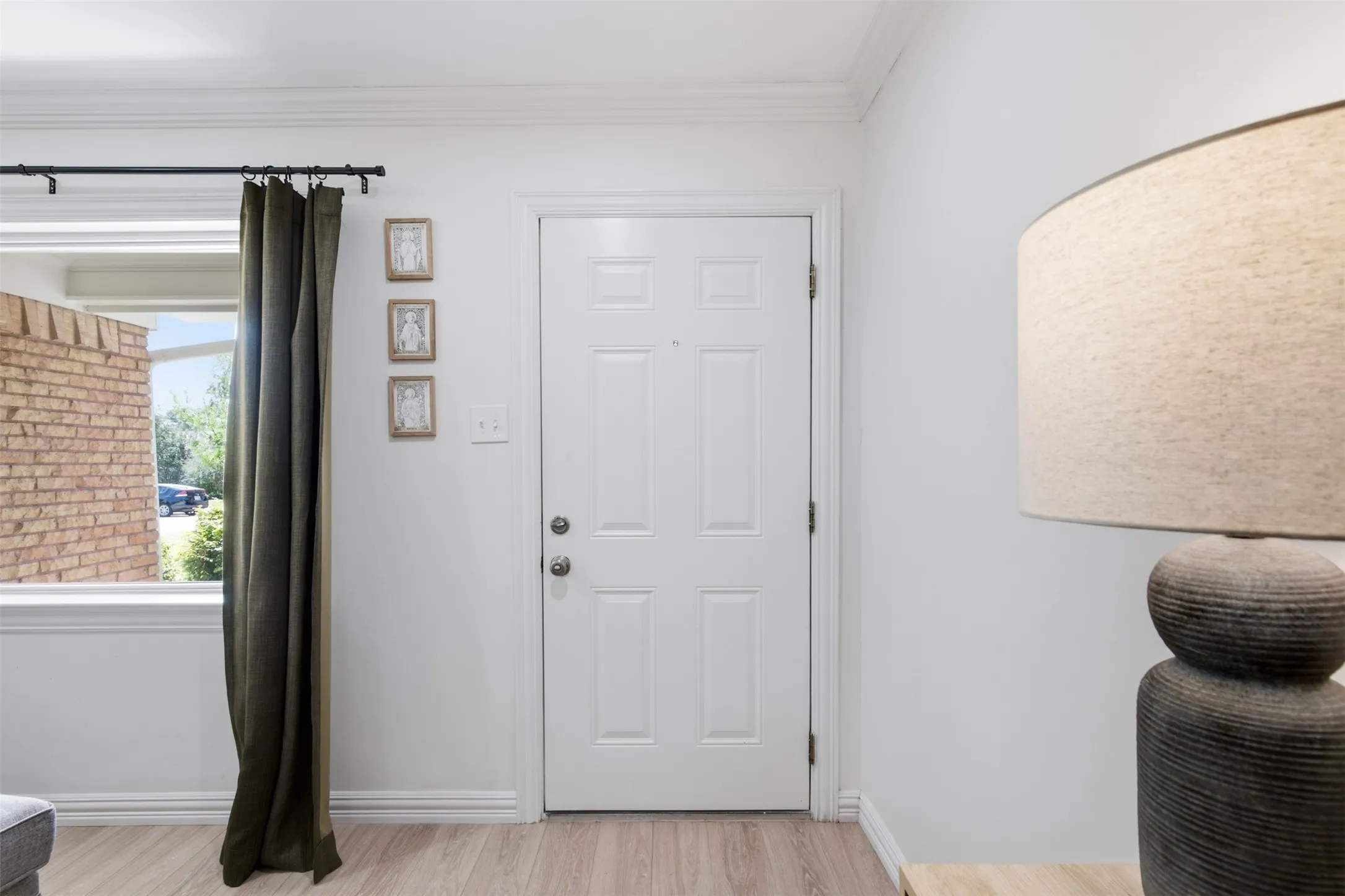 White paneled door, wood-finish flooring, and white walls