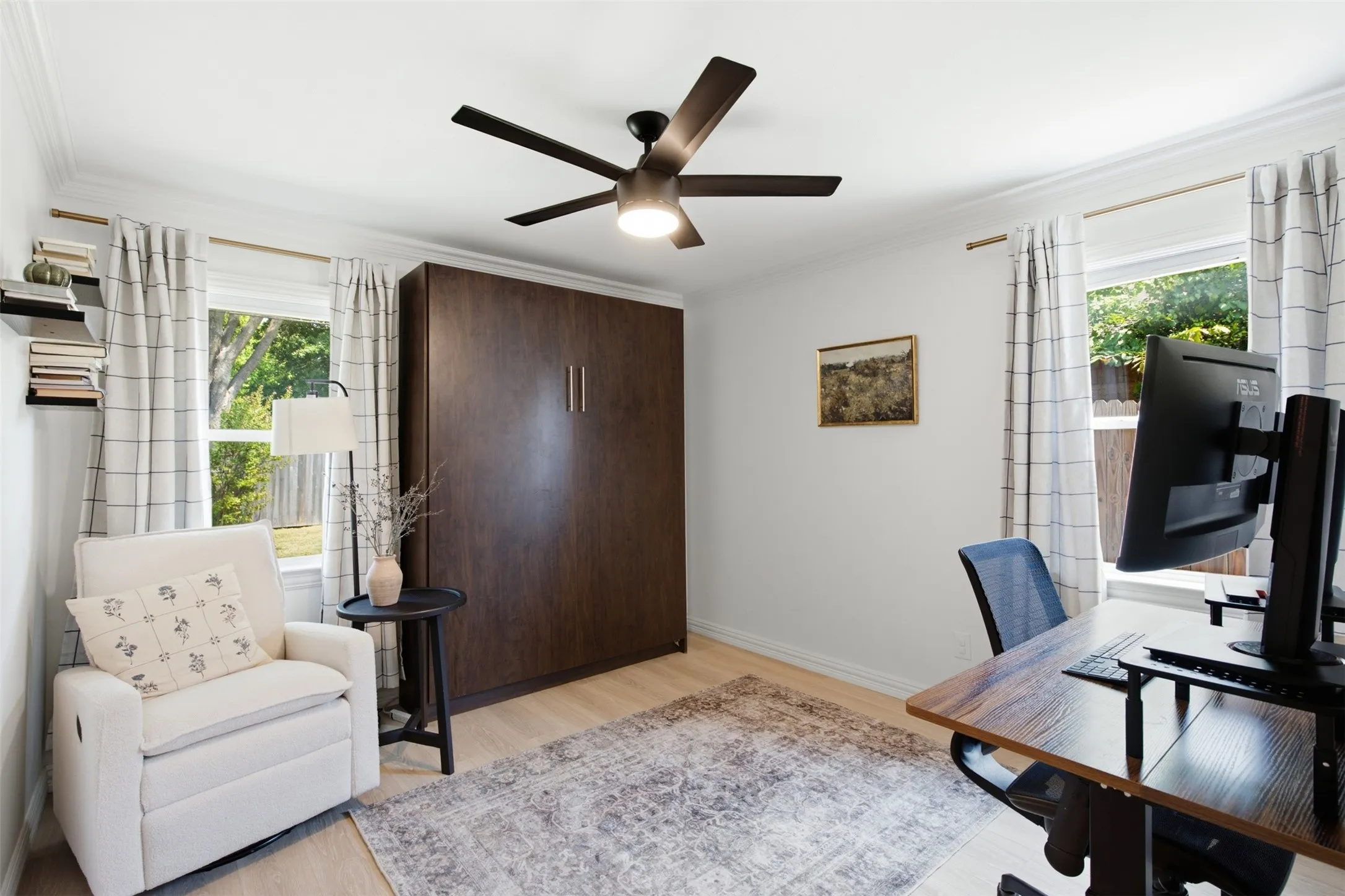 Built-in wall bed, crown molding, ceiling fan, multiple windows with natural light, and light wood-finish flooring