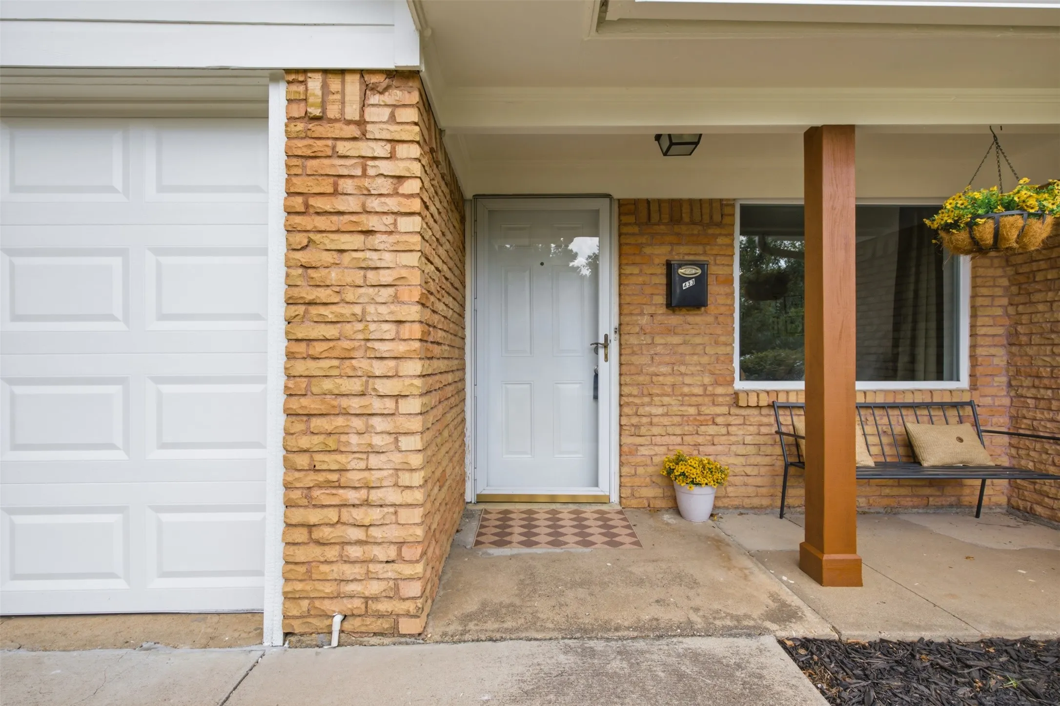 Brick facade with white paneled garage door and covered entry