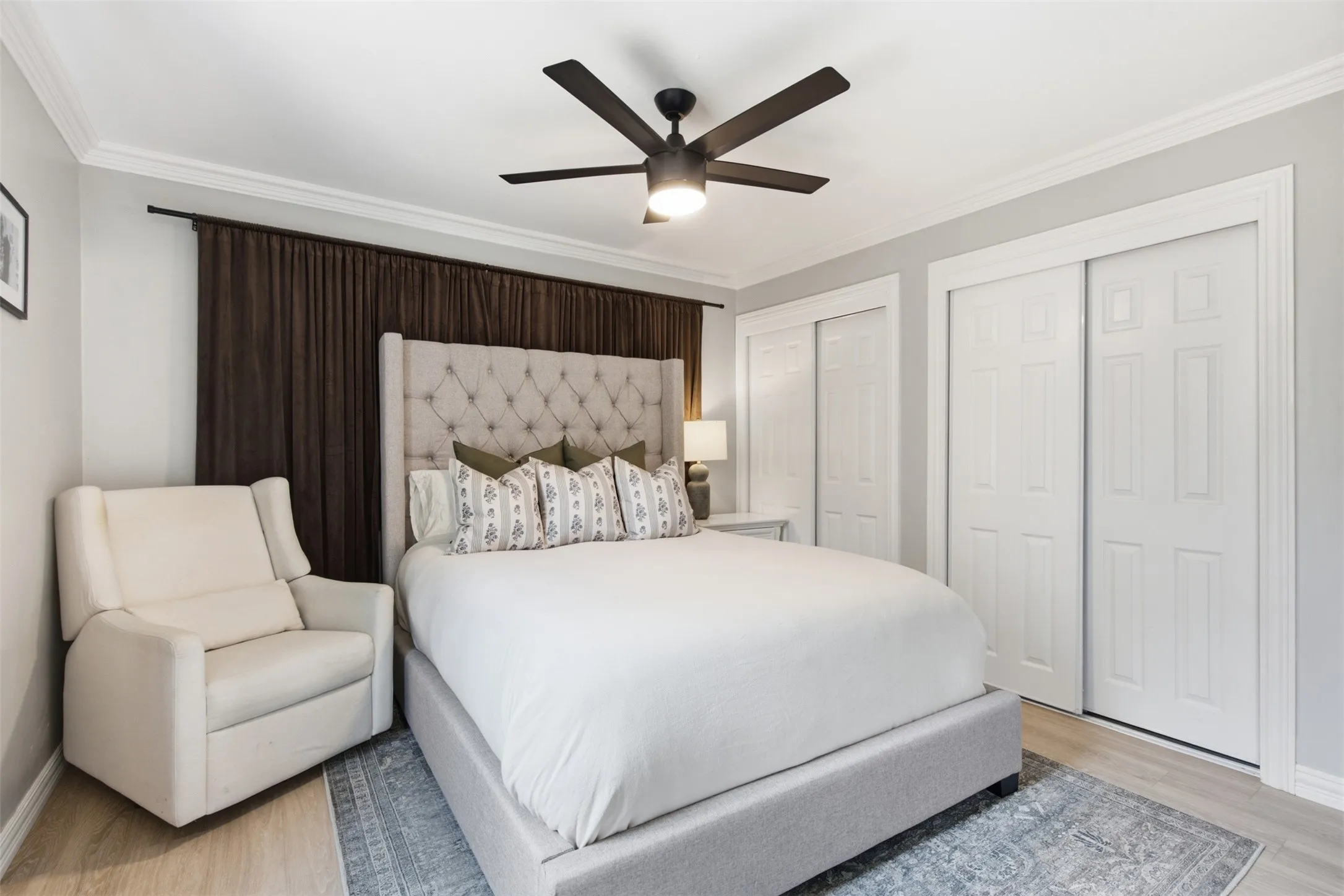 Crown molding detail, ceiling fan with integrated lighting, wood-finish flooring, and white panel doors