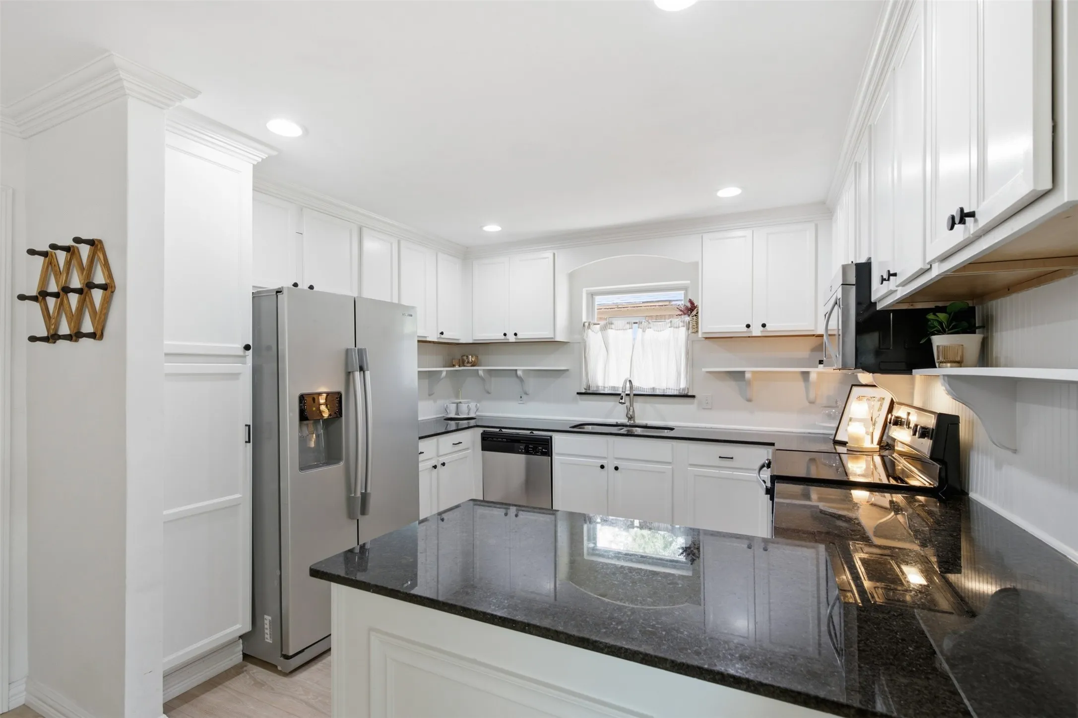 White shaker cabinetry, stainless steel appliances, dark stone countertops, recessed lighting, and crown molding