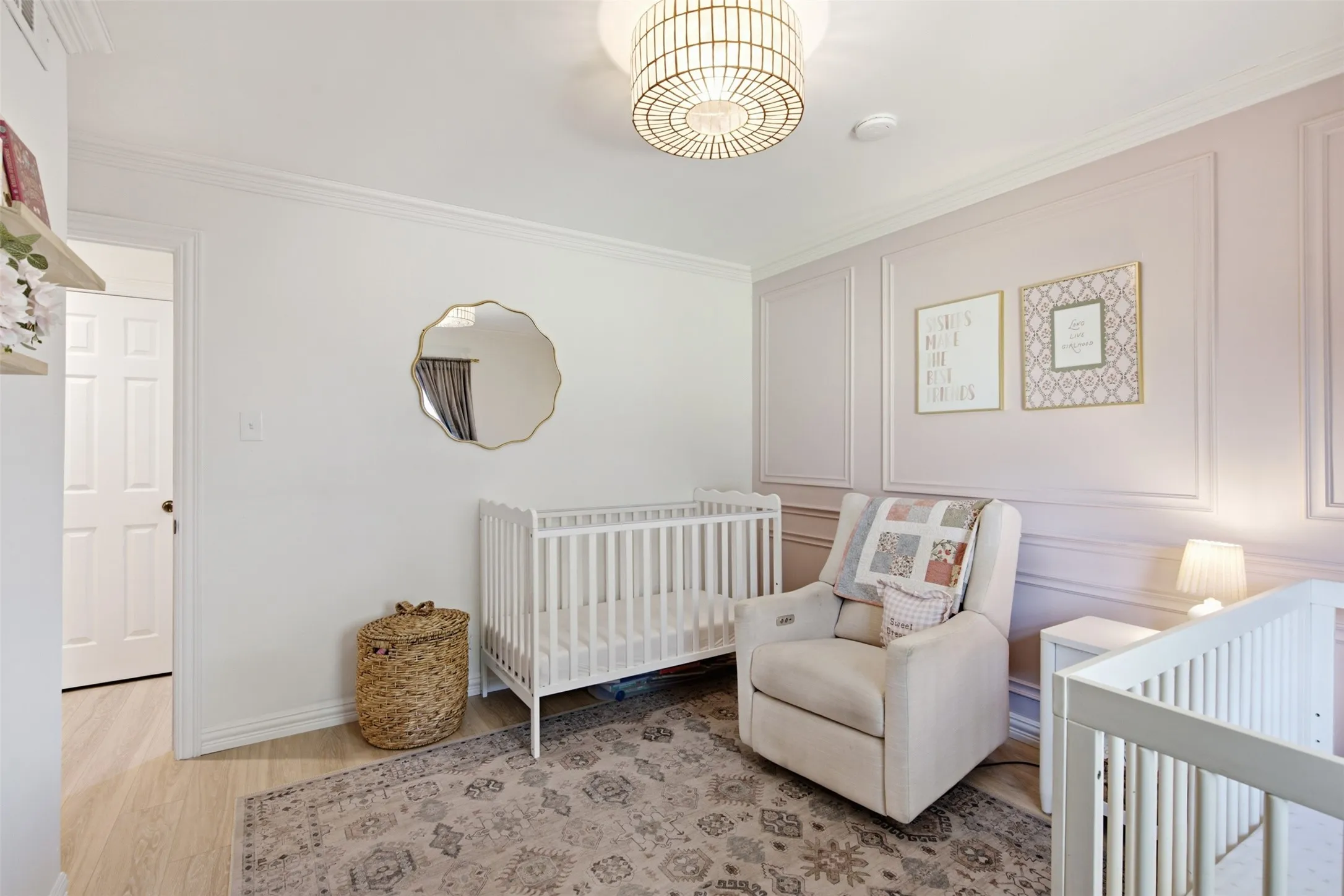 Crown molding with a light fixture, accent wall with paneling, and wood-finish flooring