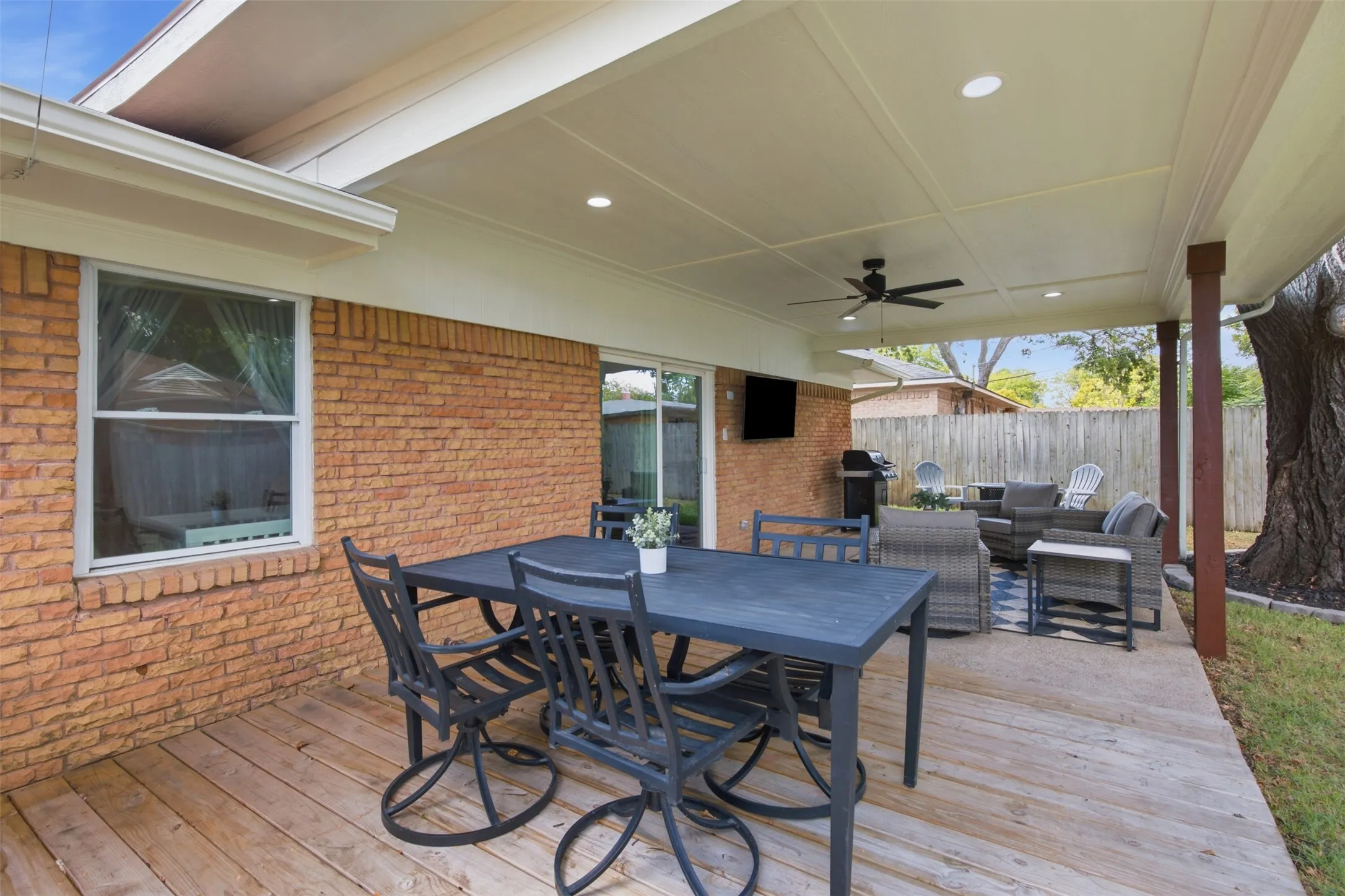 Expansive covered patio featuring a wood deck surface, recessed lighting, and a ceiling fan