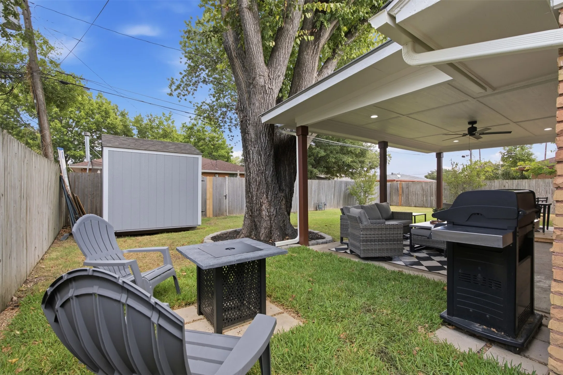 Expansive backyard featuring a covered patio, ceiling fan, recessed lighting, and a storage shed