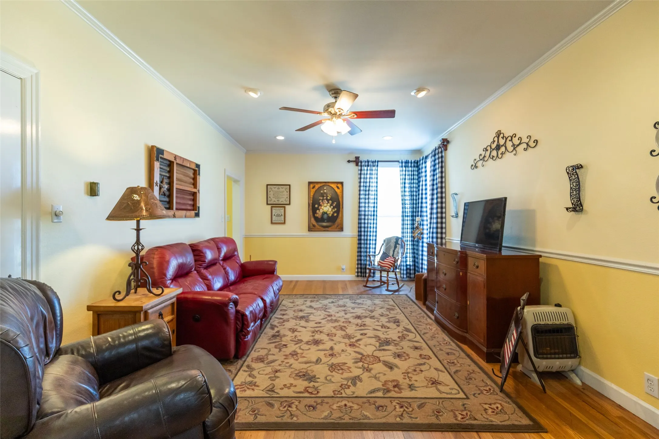 Wood-finish flooring with crown molding, a ceiling fan with integrated lighting, and recessed lighting