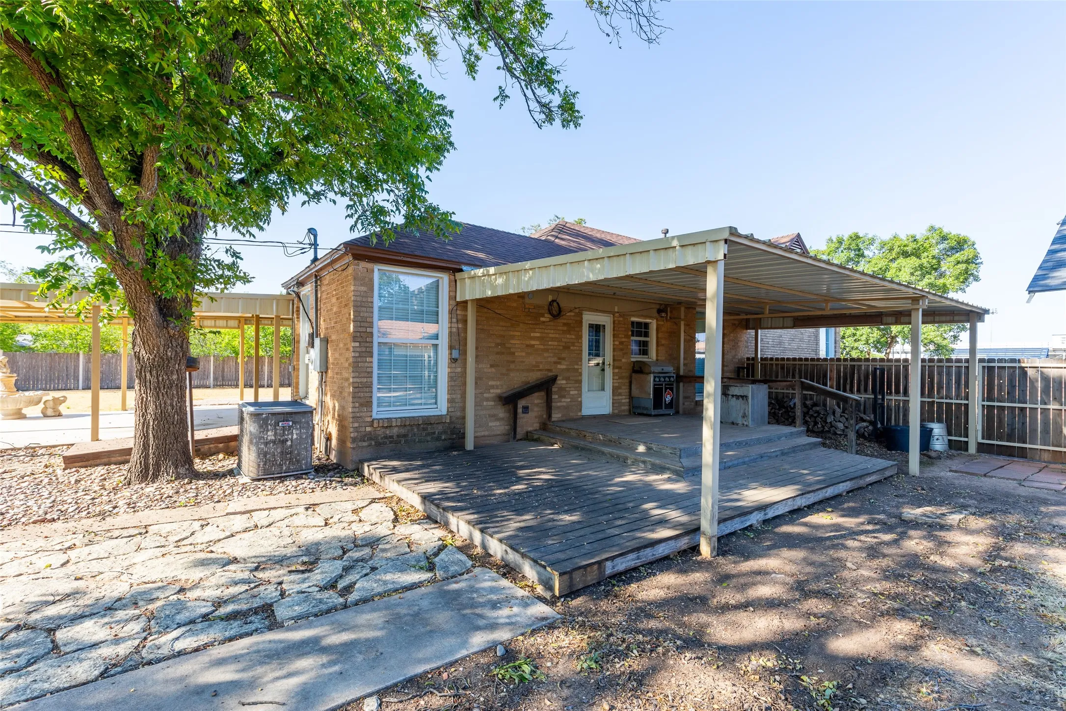 Brick exterior with a covered patio, wood-finish decking, and a fenced yard