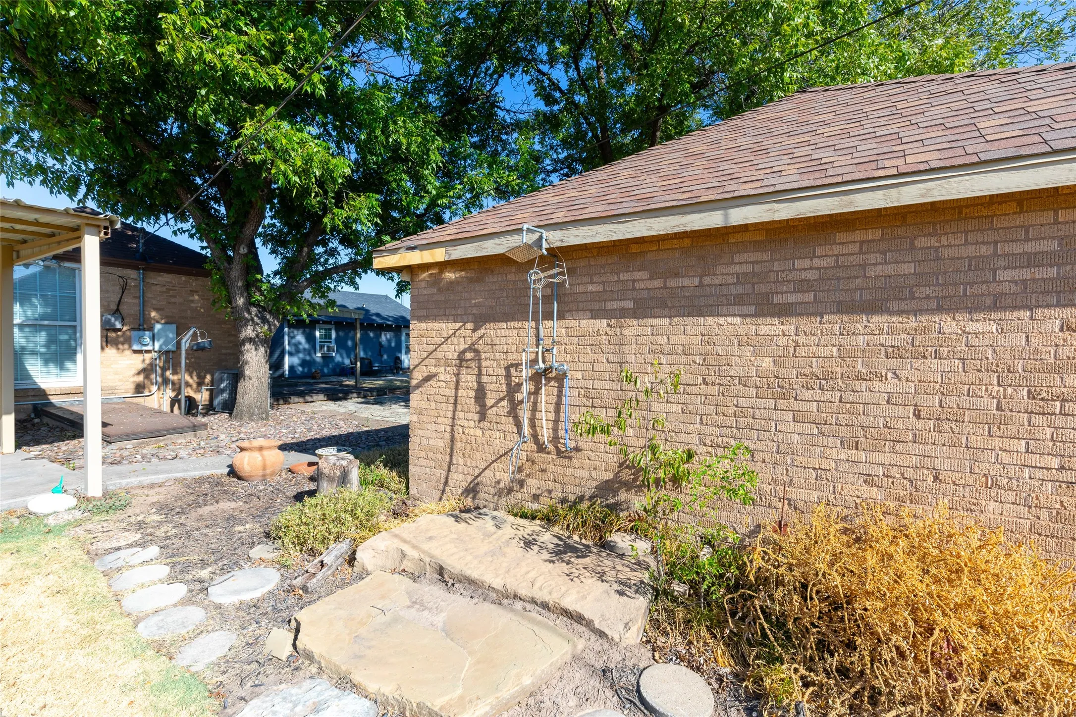 Brick exterior wall with a shingle roof and a stone step pathway
