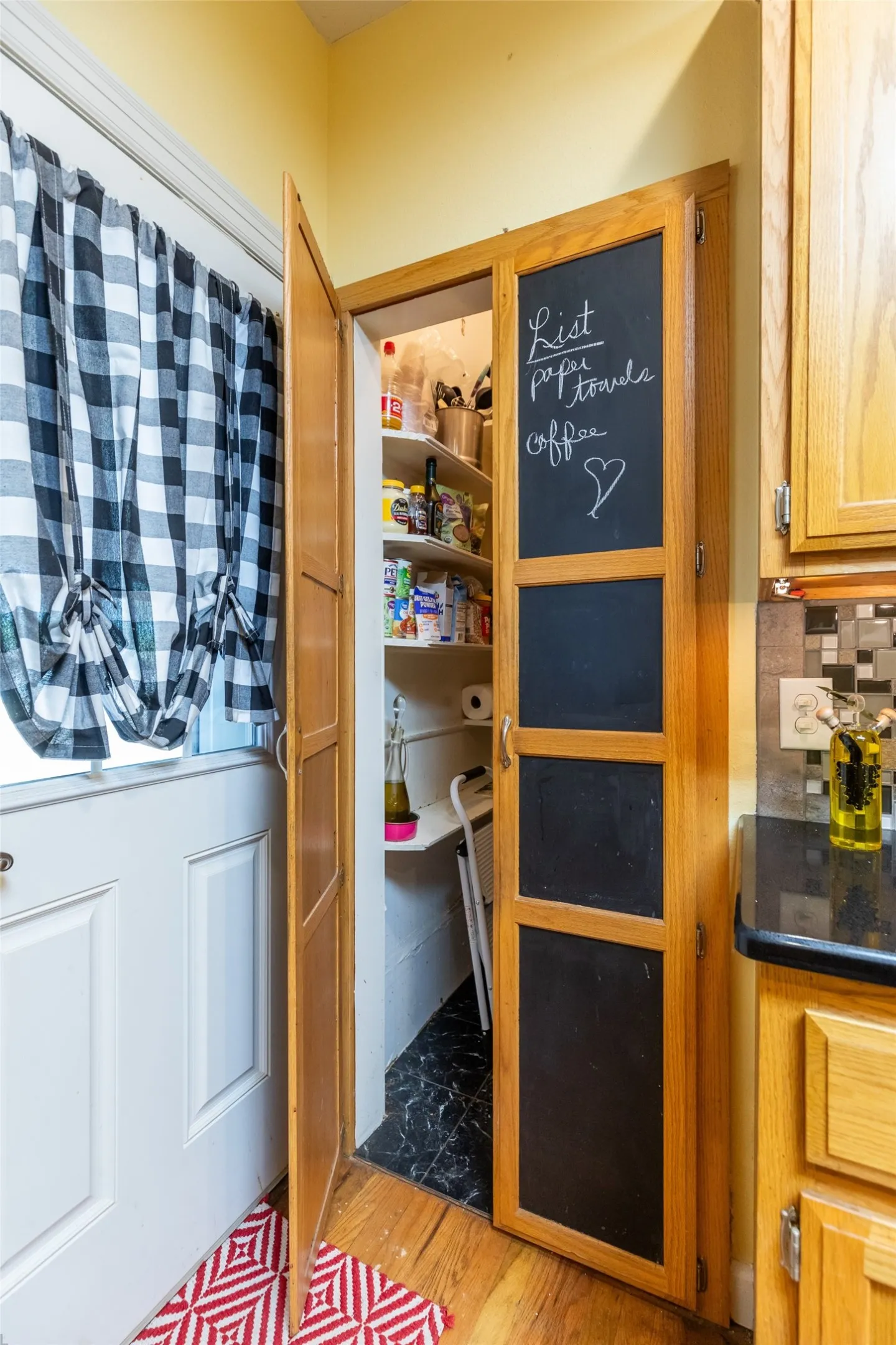 Pantry with wood-finish shelving and a black and white tile floor