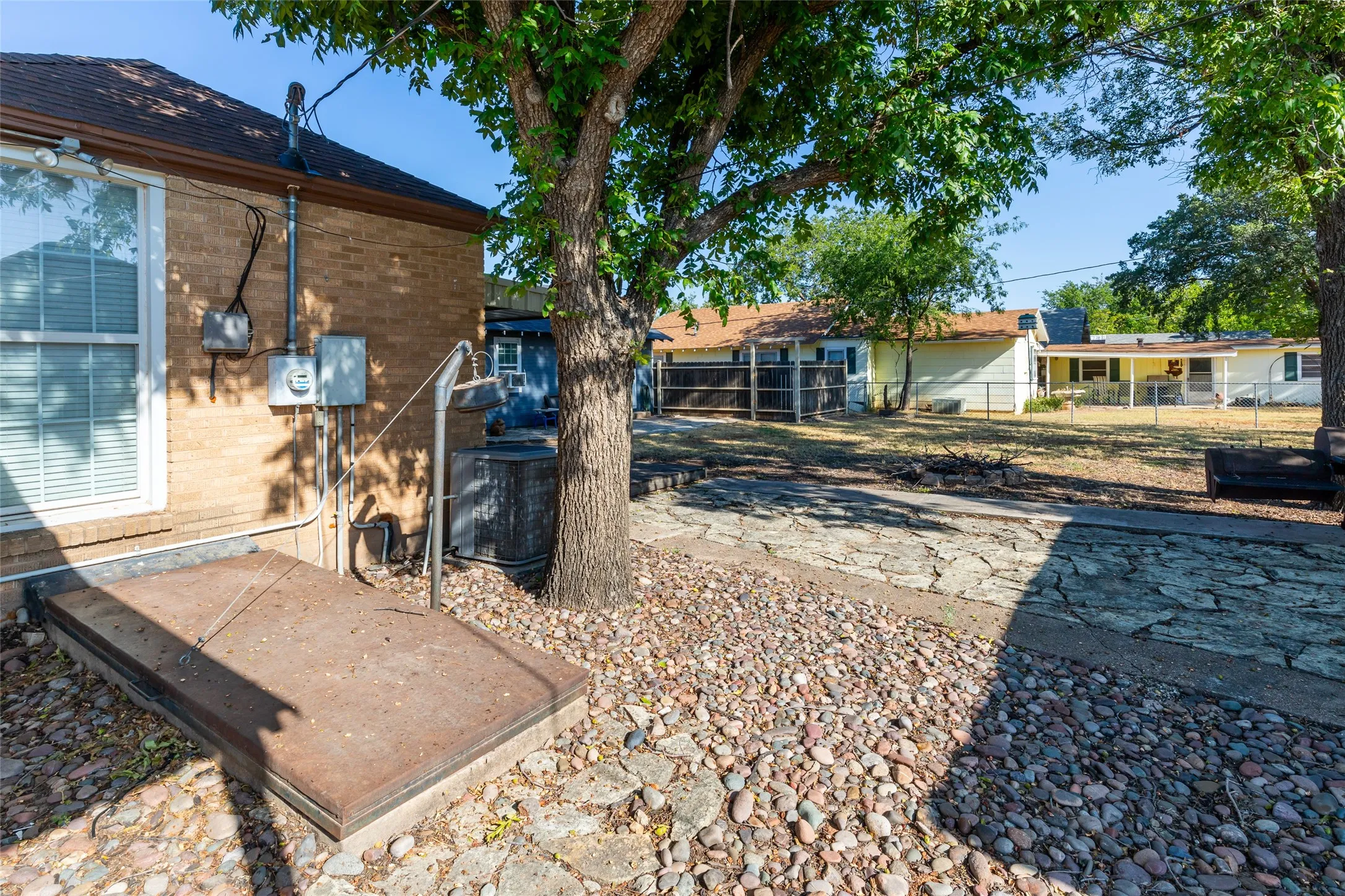 Brick exterior with a window featuring horizontal blinds & Exterior storm shelter entrance/hatch
