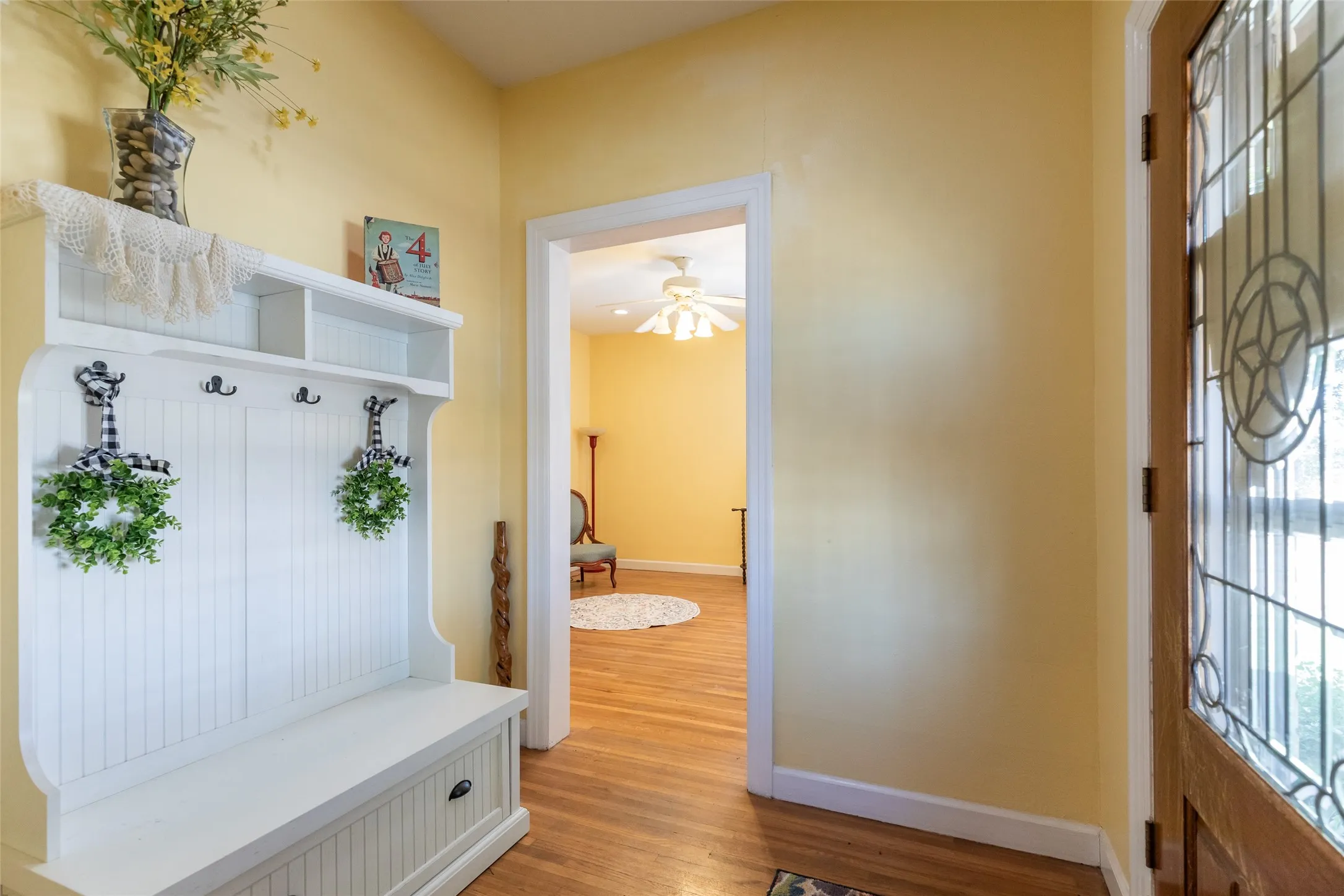 Entryway featuring a decorative transom door, wood-finish flooring, and a built-in coat rack with bench seating