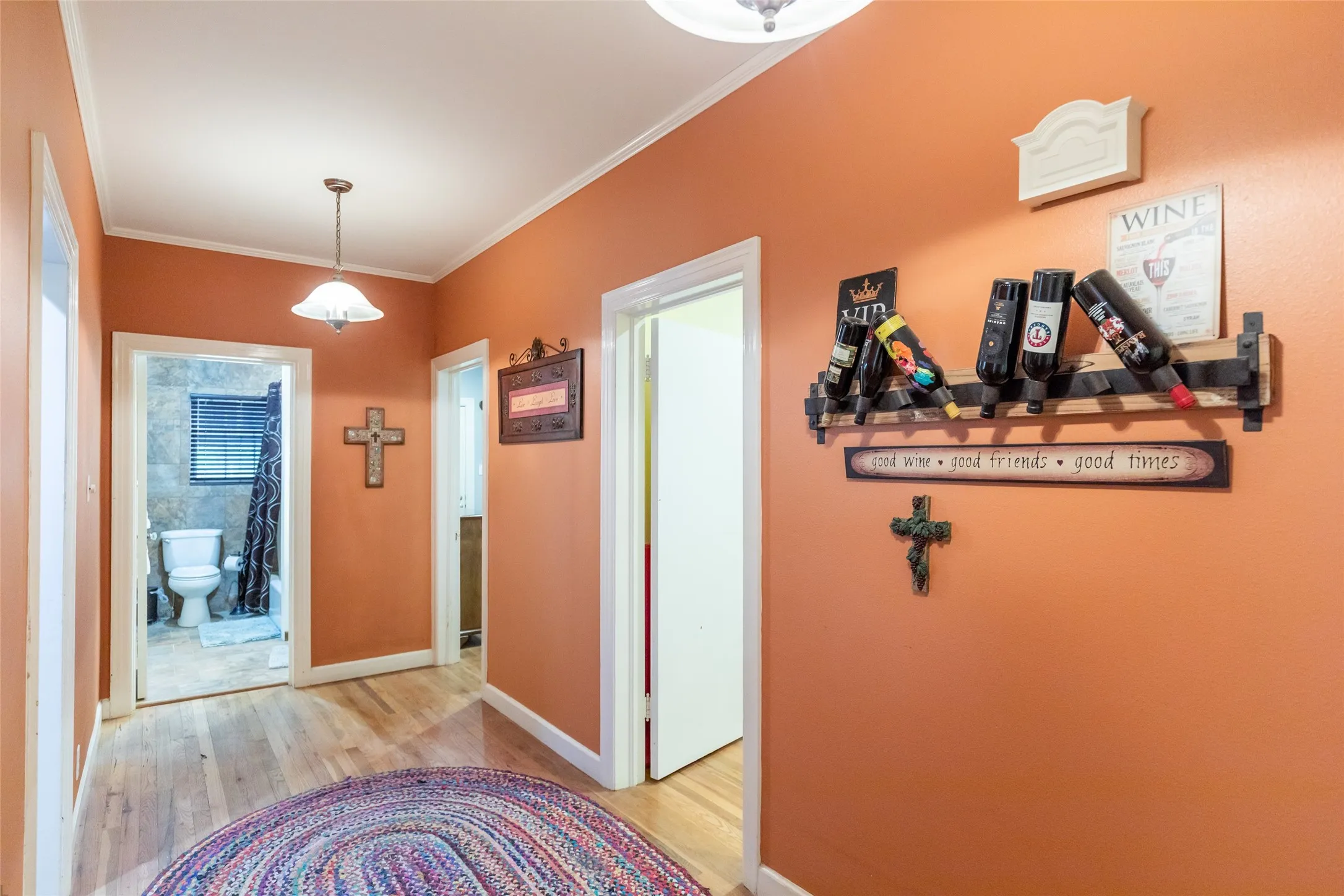 Hallway with wood-finish flooring, overhead pendant light, and white trim