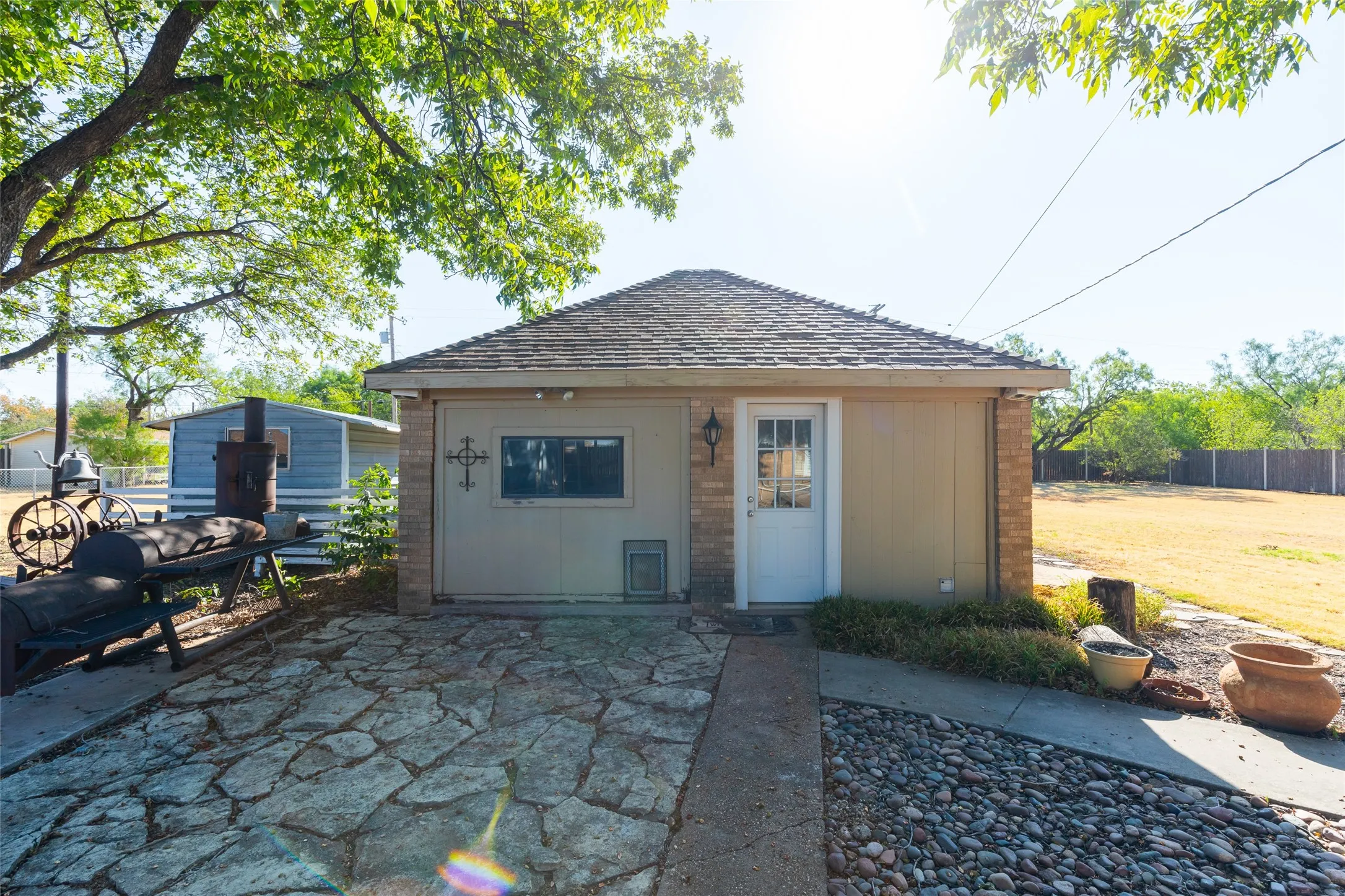Detached structure featuring a shingle roof, exterior lighting fixture, and a paneled door