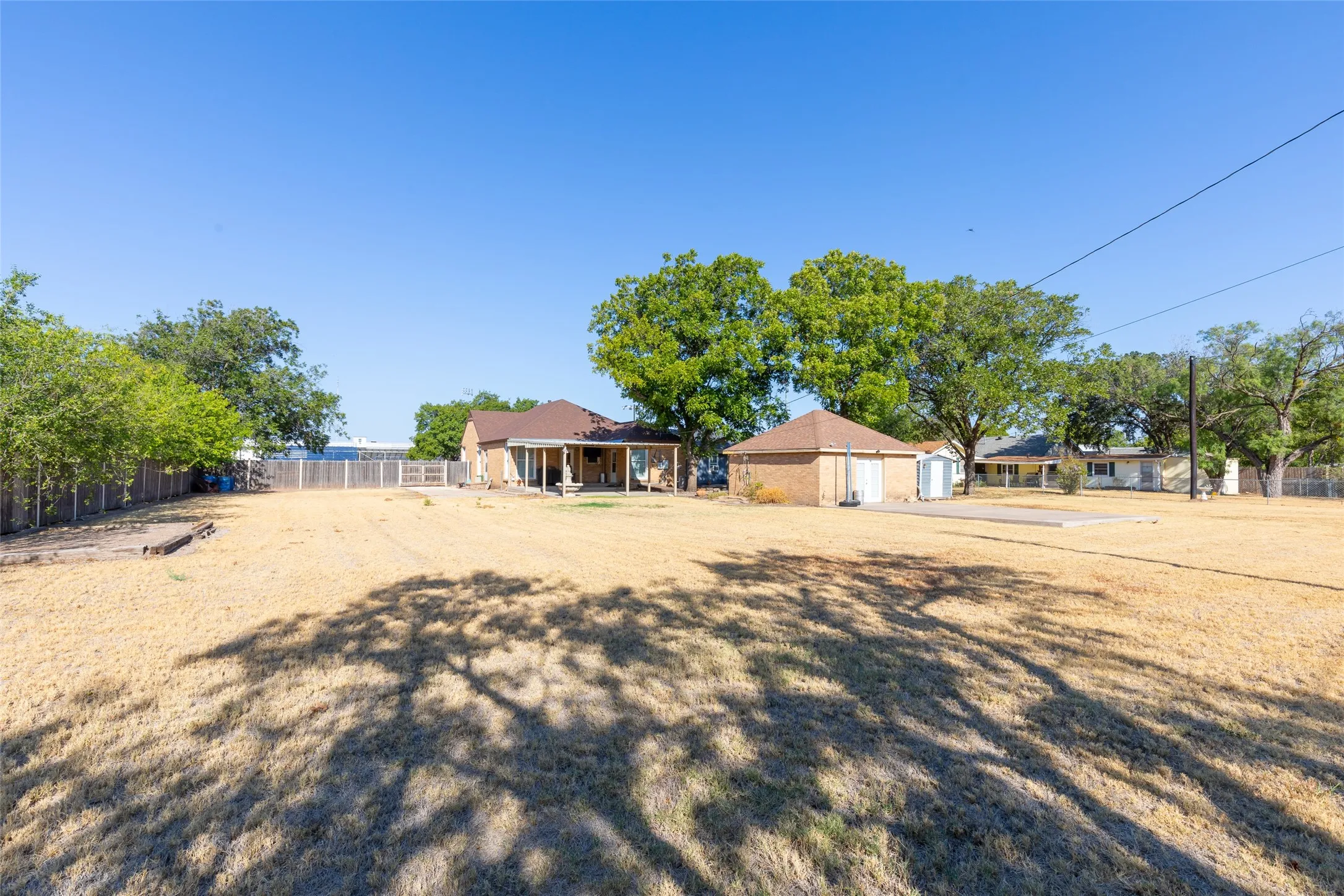 Expansive outdoor space featuring a detached garage, a covered patio, and a privacy fence