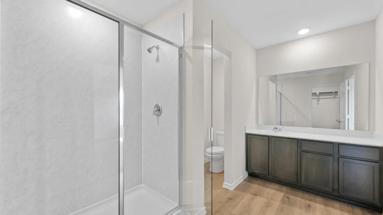 Modern bathroom featuring a glass-enclosed shower with white paneling and chrome fixtures