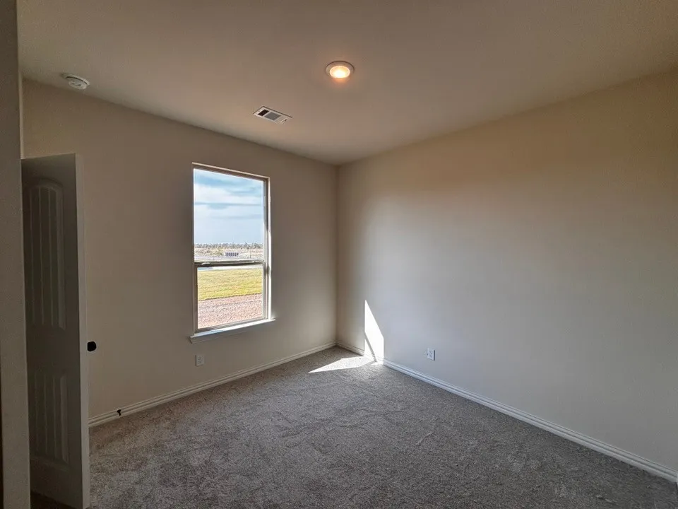 Neutral wall finishes, recessed ceiling lighting, textured carpeting, and a single window