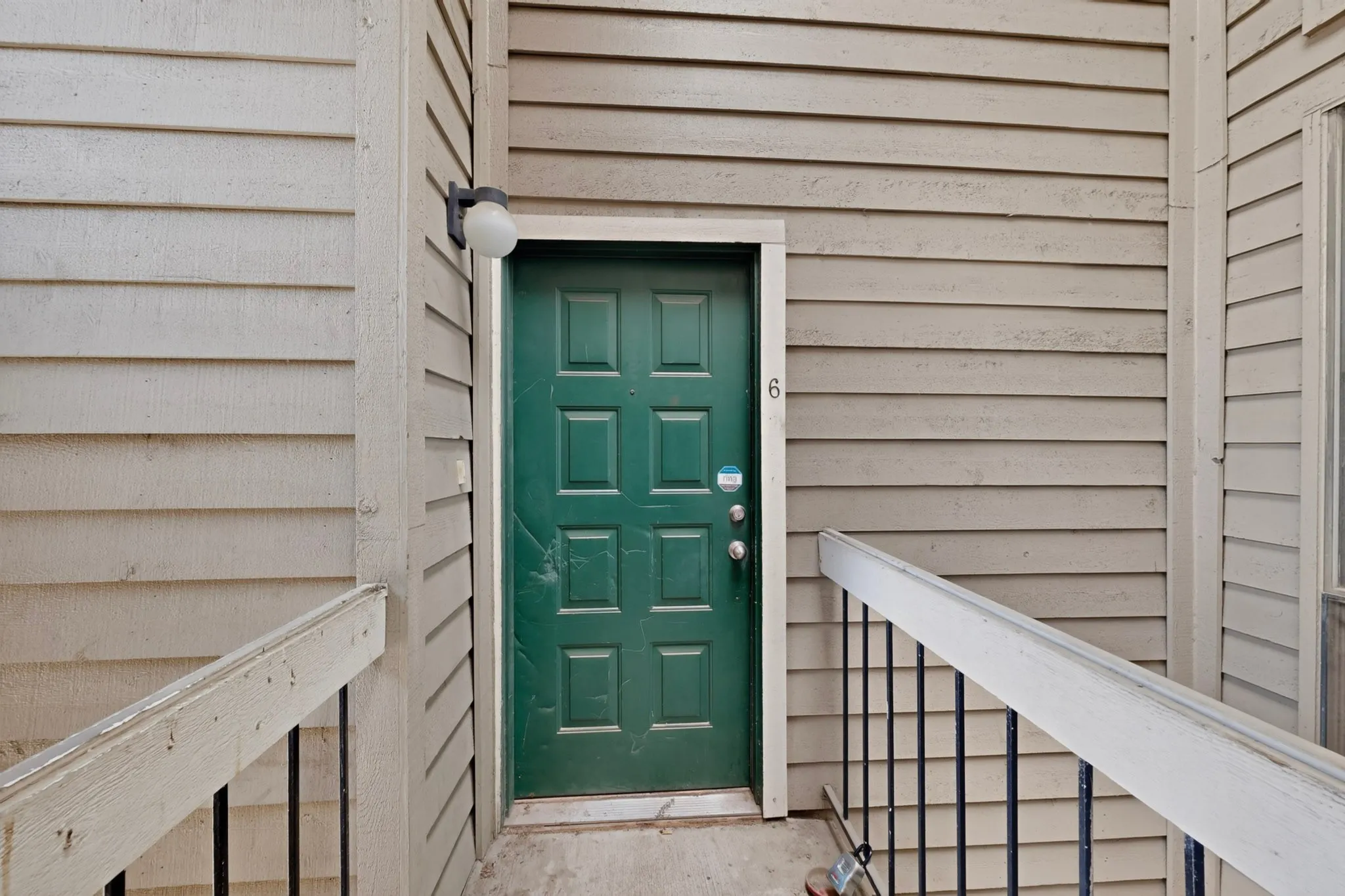 Six-panel entry door with a multi-paneled design and exterior light fixture