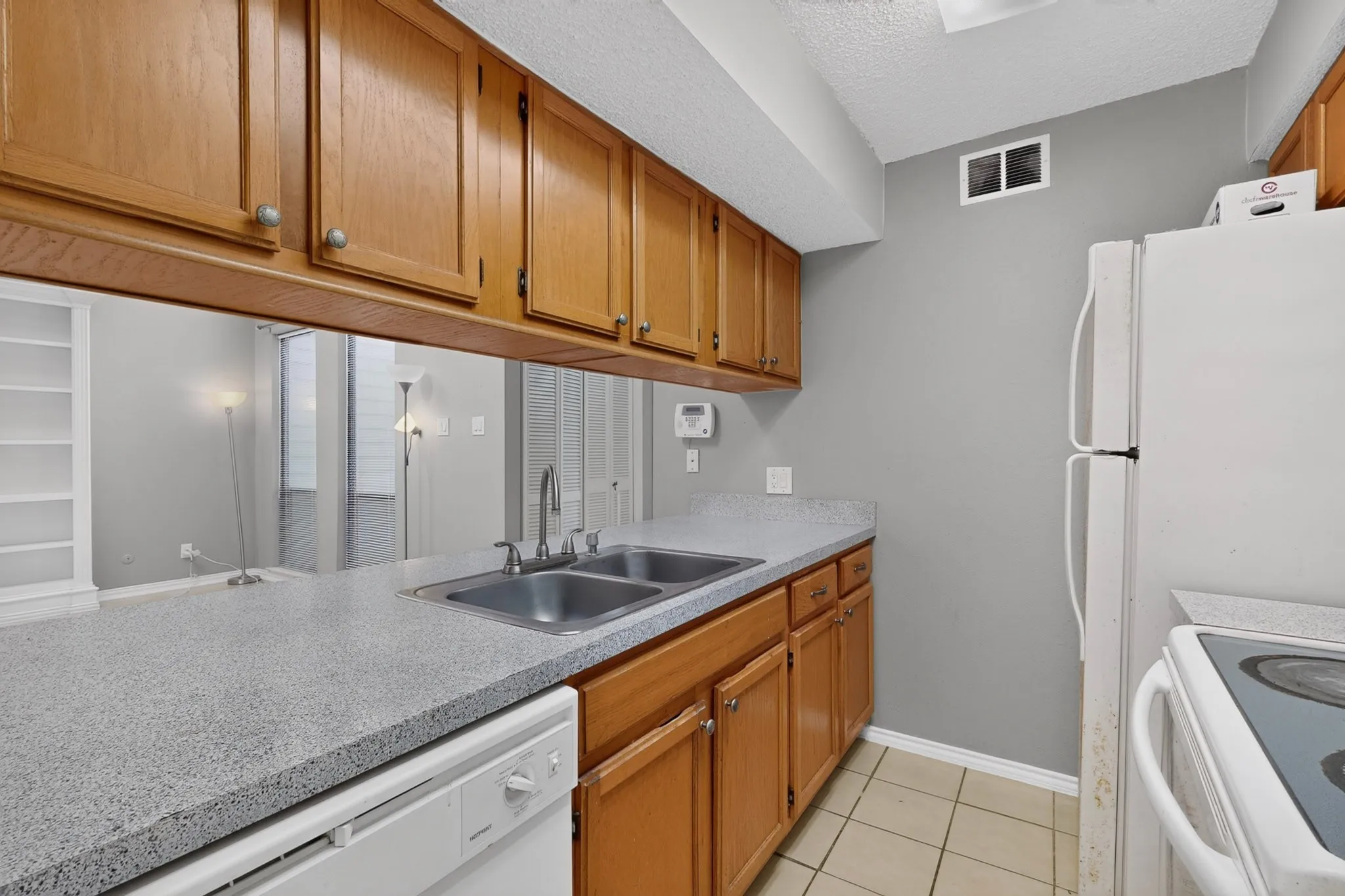 Kitchen featuring wood-finish cabinetry, light-toned countertops, and a double basin sink with a chrome faucet