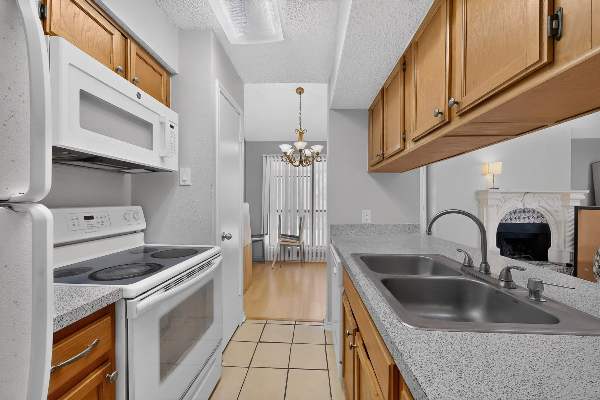 Kitchen with wood cabinetry, light-toned countertops, and a double basin sink