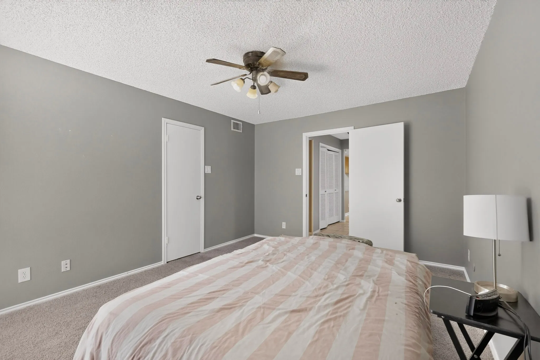 Carpeted flooring, neutral wall paint, ceiling fan light fixture, and white interior doors
