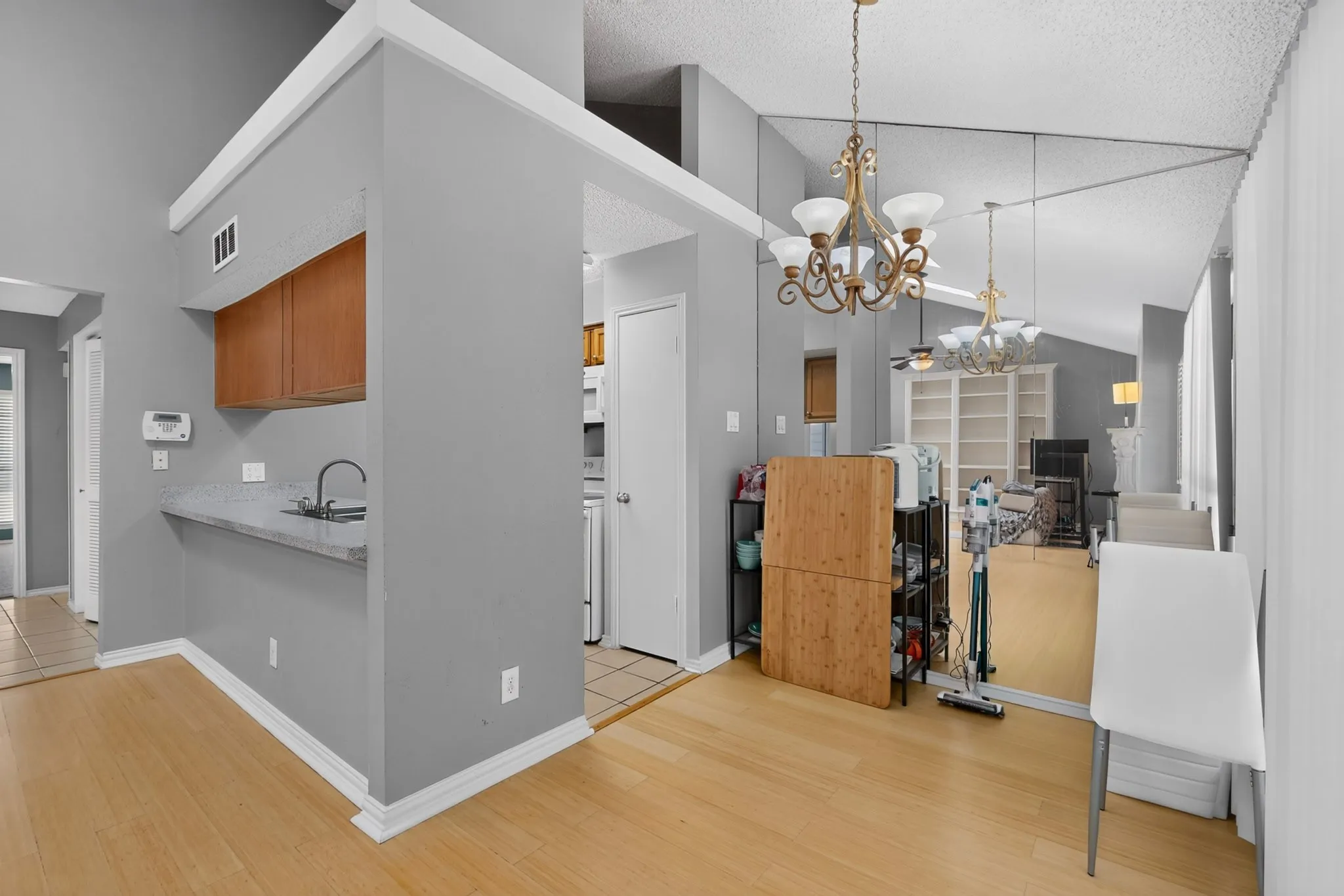 Wood-finish flooring throughout, complemented by a vaulted ceiling and a decorative chandelier