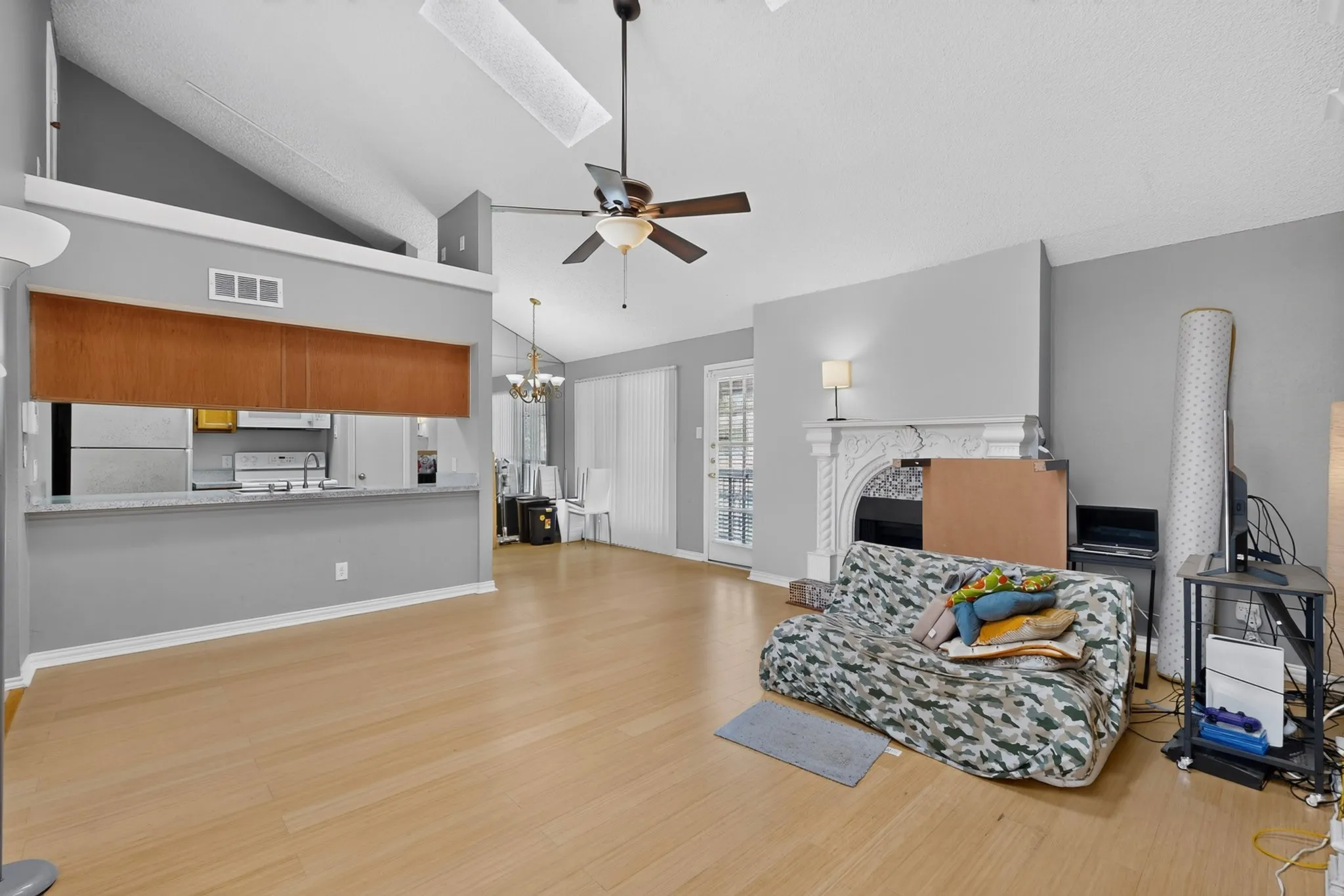 Vaulted ceilings, wood-finish flooring, a decorative fireplace, and an open-concept pass-through to the kitchen with a breakfast bar