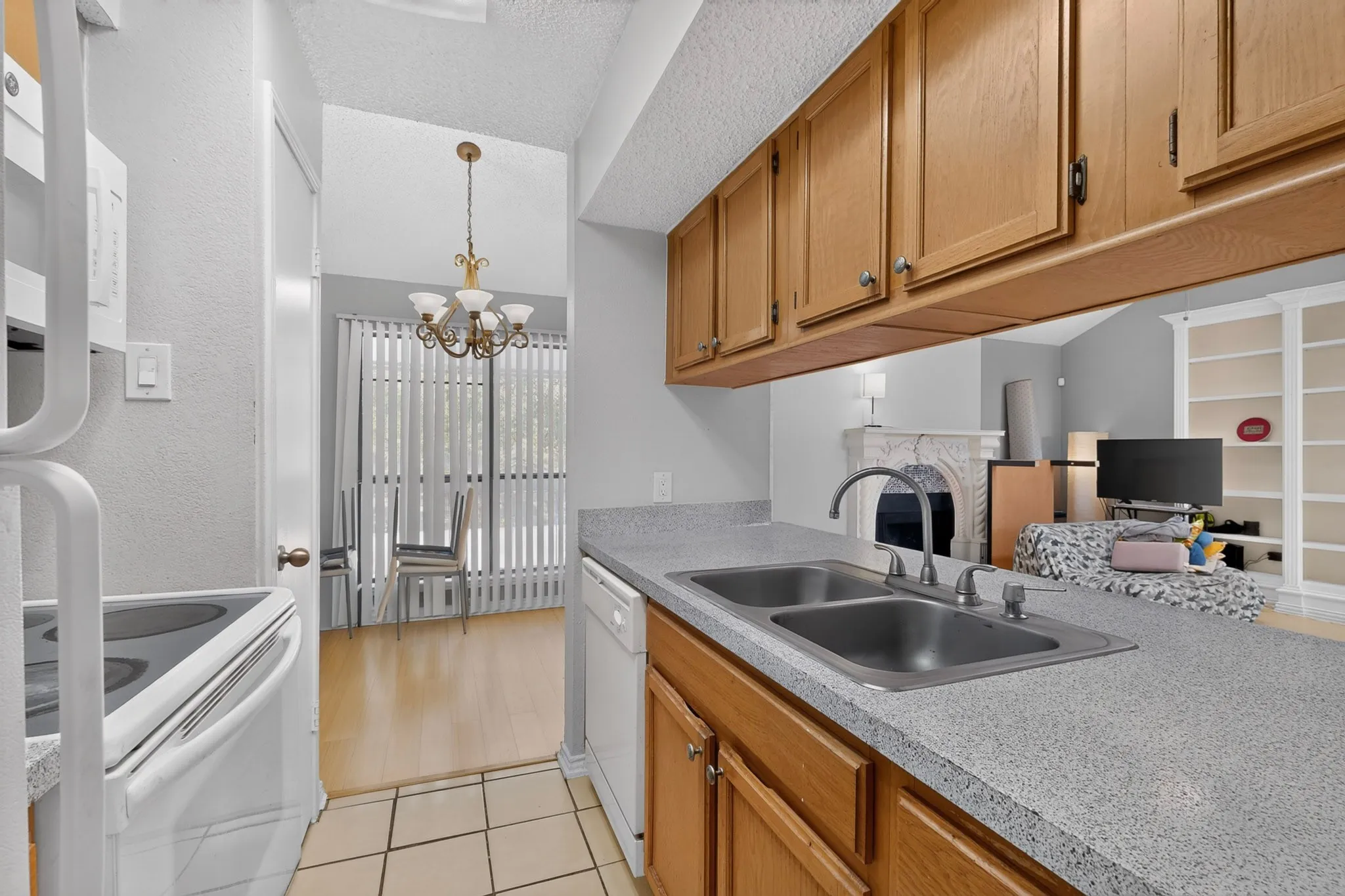 Kitchen featuring light wood cabinetry, dual-basin stainless steel sink, and light speckled countertops