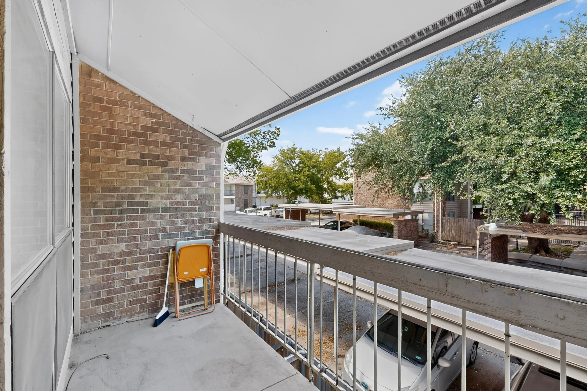 Covered outdoor balcony with concrete flooring, brick wall, and metal railing
