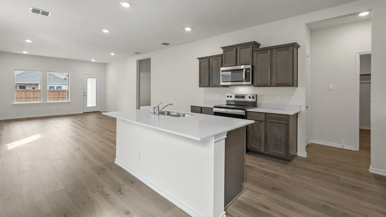 Open-concept kitchen featuring an island with a sink, wood-finish flooring, recessed lighting, white countertops, and dark wood cabinetry