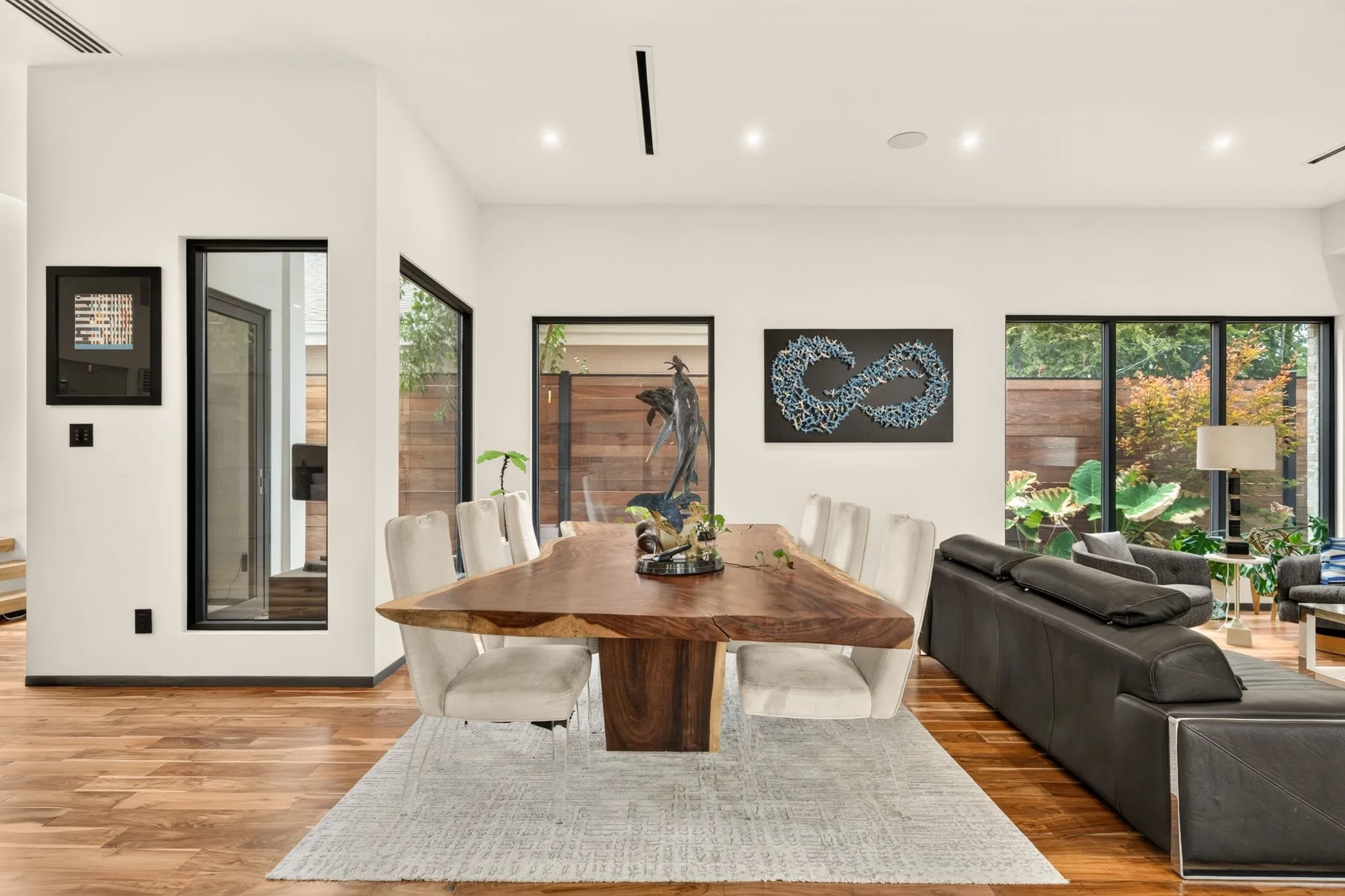Hardwood flooring, recessed ceiling lighting, large windows with black frames, white walls, and high ceilings