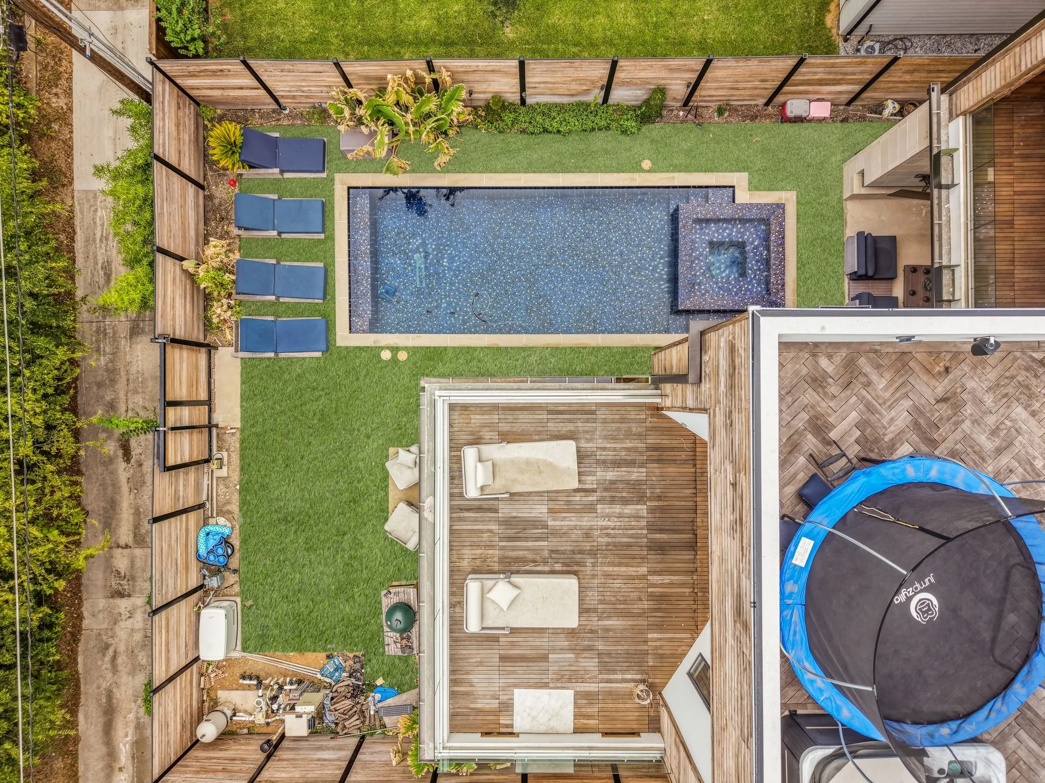 Outdoor living space featuring a rectangular pool, integrated spa, artificial turf, and a wood-slat privacy fence