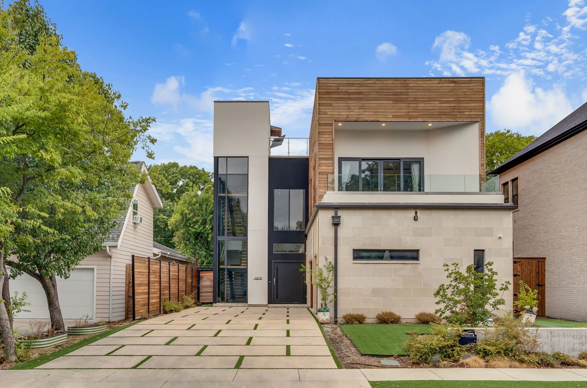 Modern multi-story exterior with wood paneling, large format stone block, and expansive glass windows