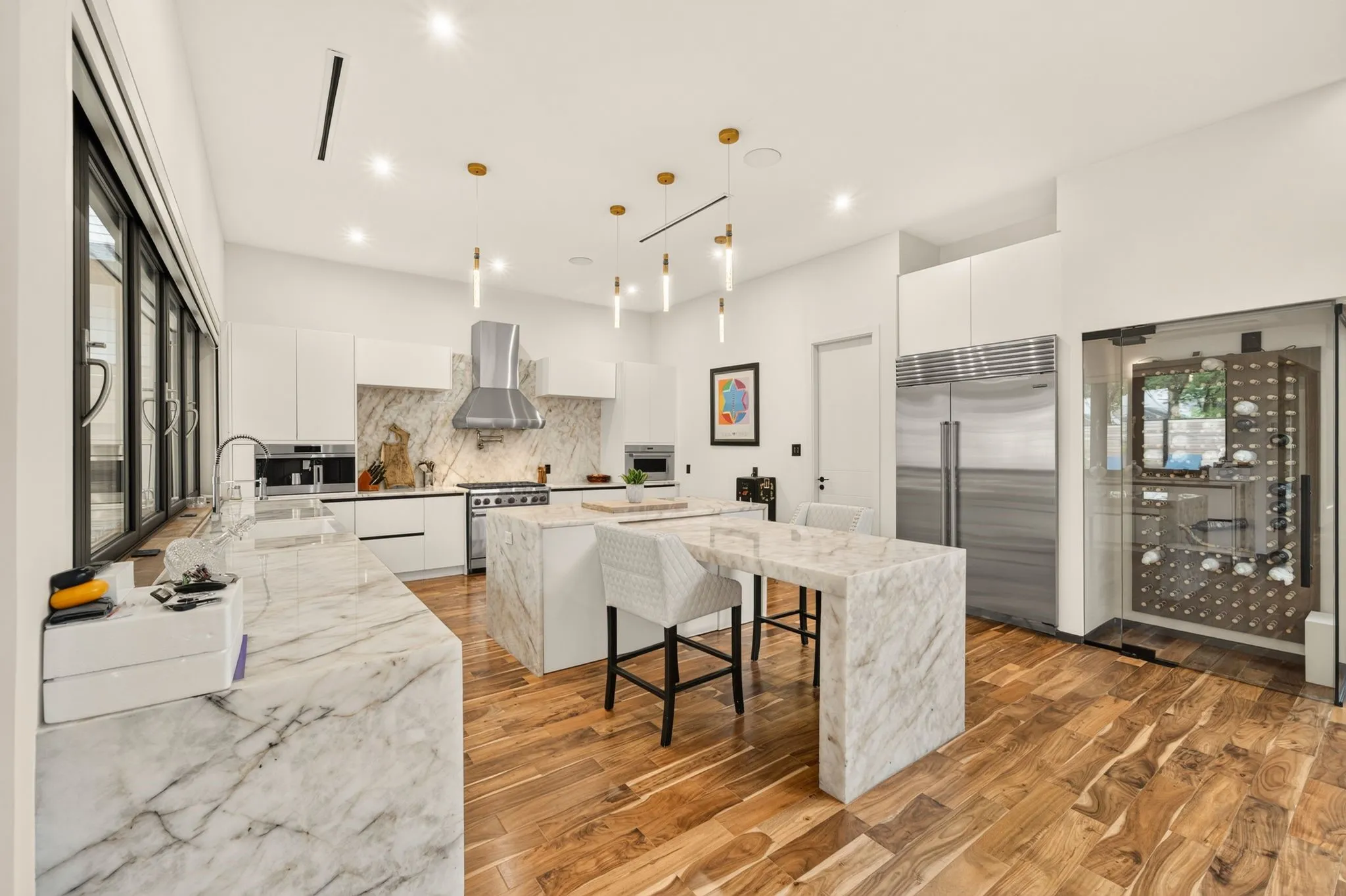 Spacious kitchen with wood-finish flooring, white cabinetry, and stone countertops