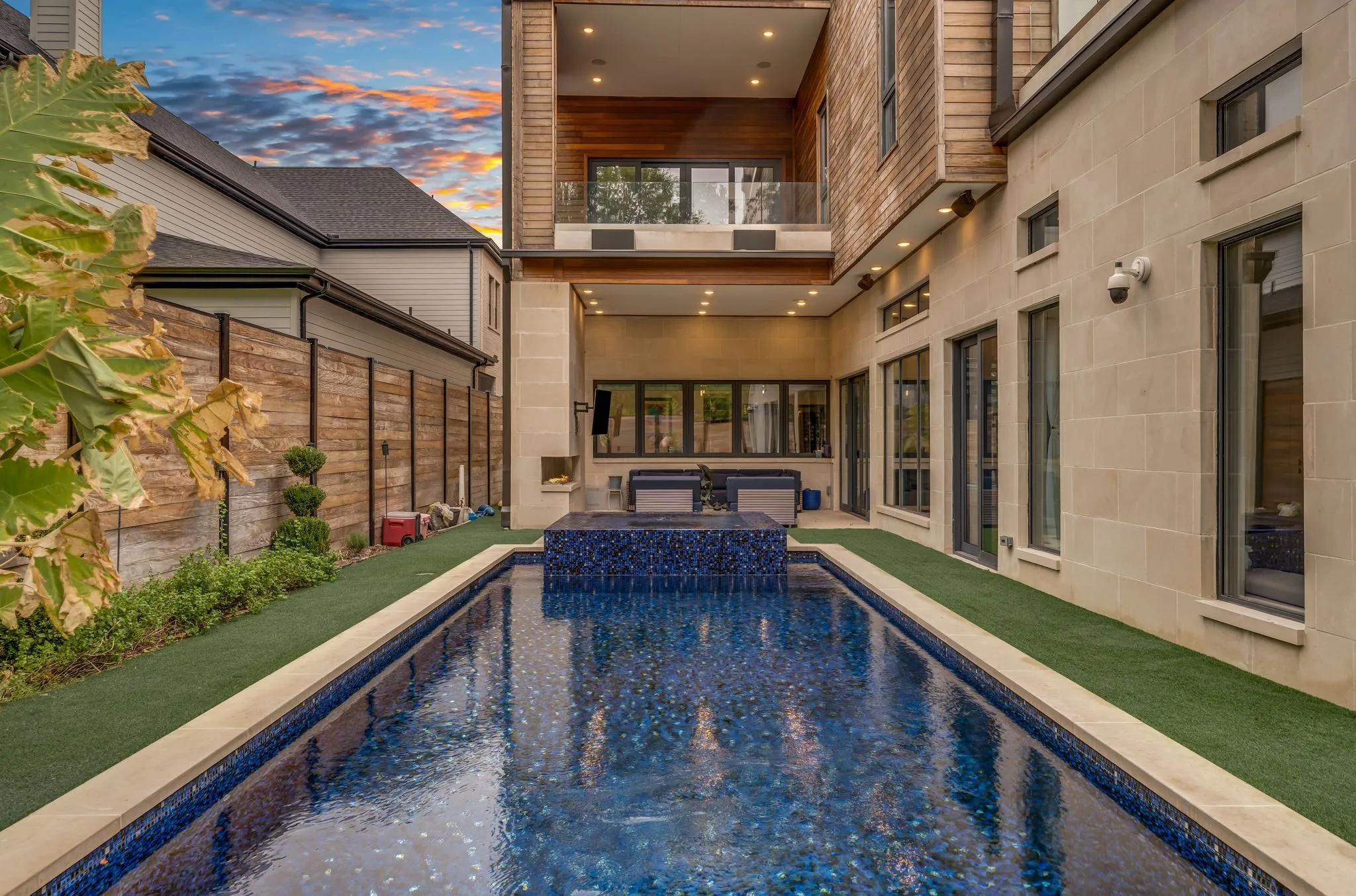 Rectangular swimming pool with dark blue tile, stone coping, and a built-in spa