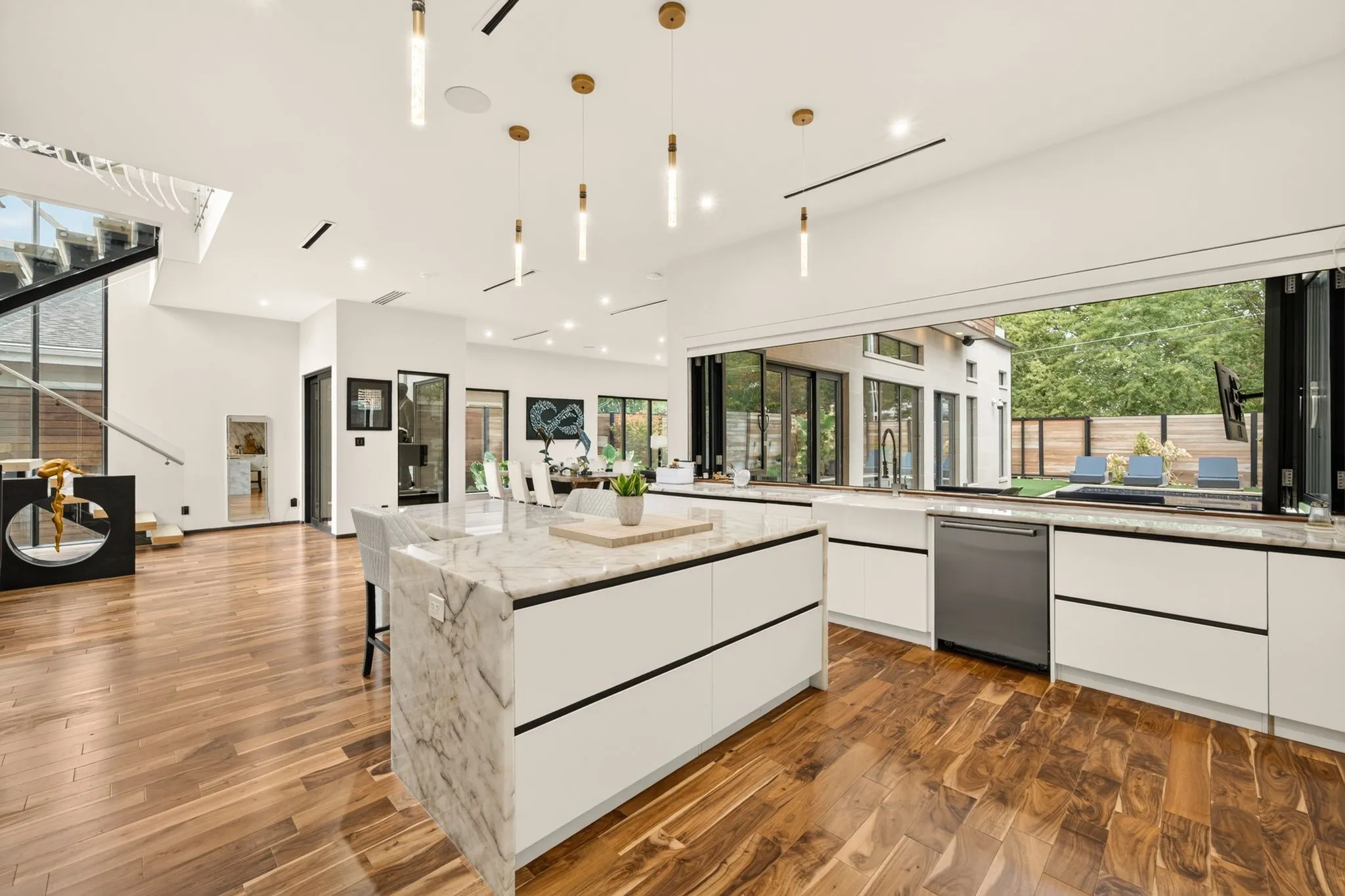 Gourmet kitchen with a waterfall island, sleek flat-panel cabinetry, stainless steel dishwasher, and expansive folding glass doors
