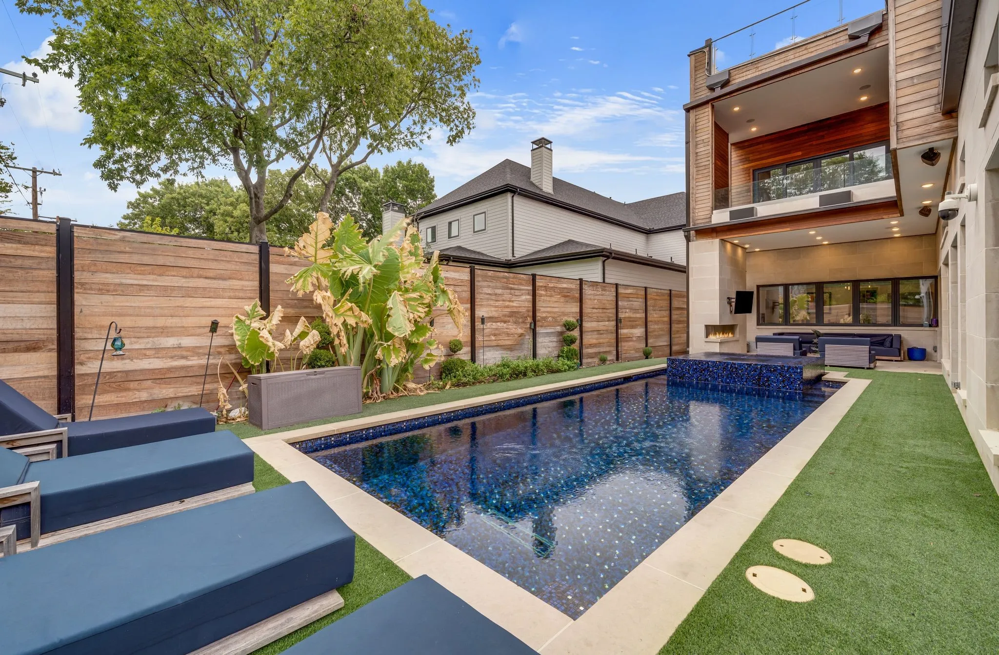 Backyard with a rectangular swimming pool, integrated spa, artificial turf, and a wood privacy fence