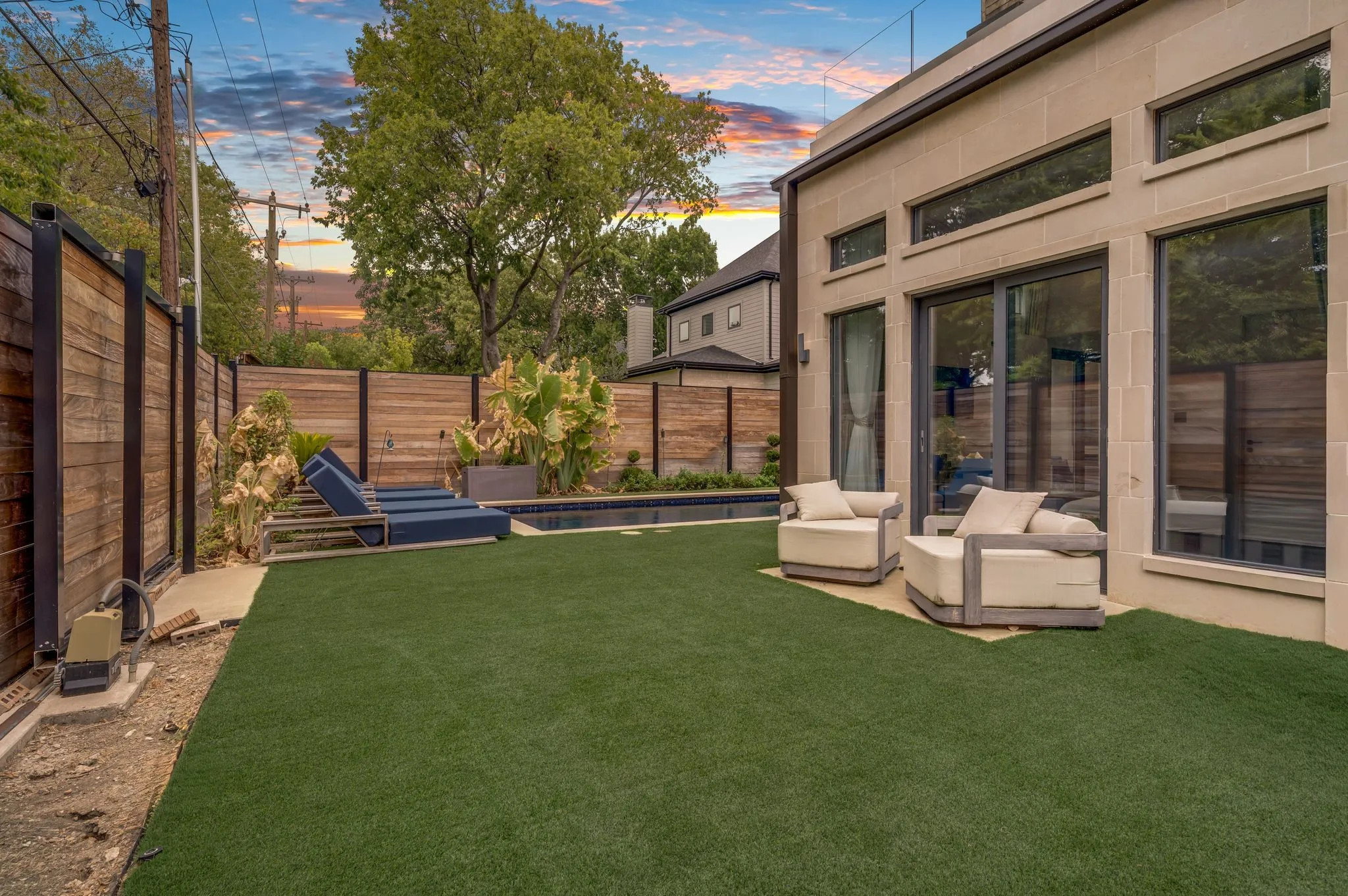 Exterior featuring a substantial patio, sliding glass doors, upper transom windows, and a landscaped yard with a privacy fence