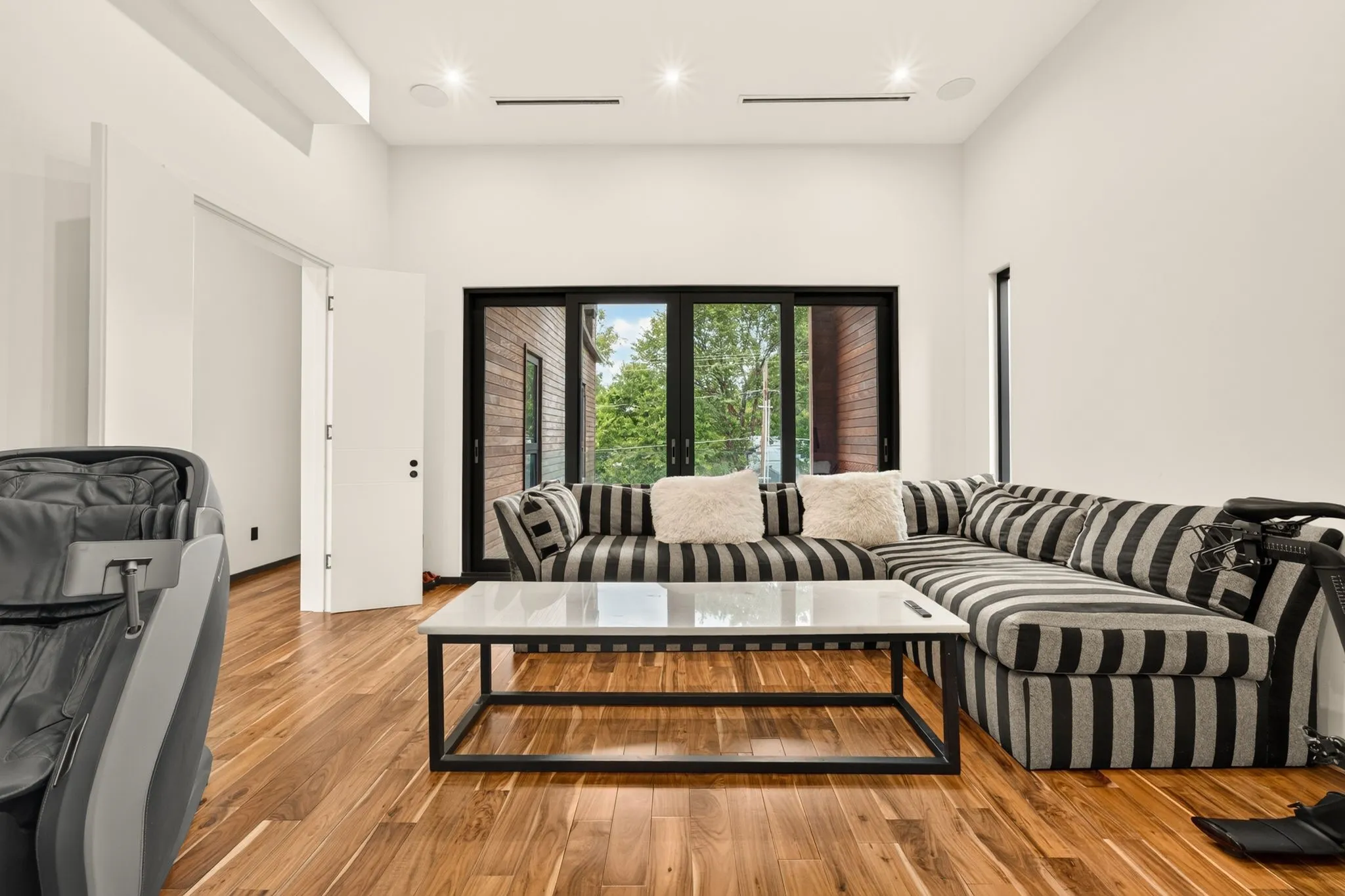 Expansive wood-finish flooring throughout, complemented by a floor-to-ceiling sliding glass door, high ceilings, and recessed lighting