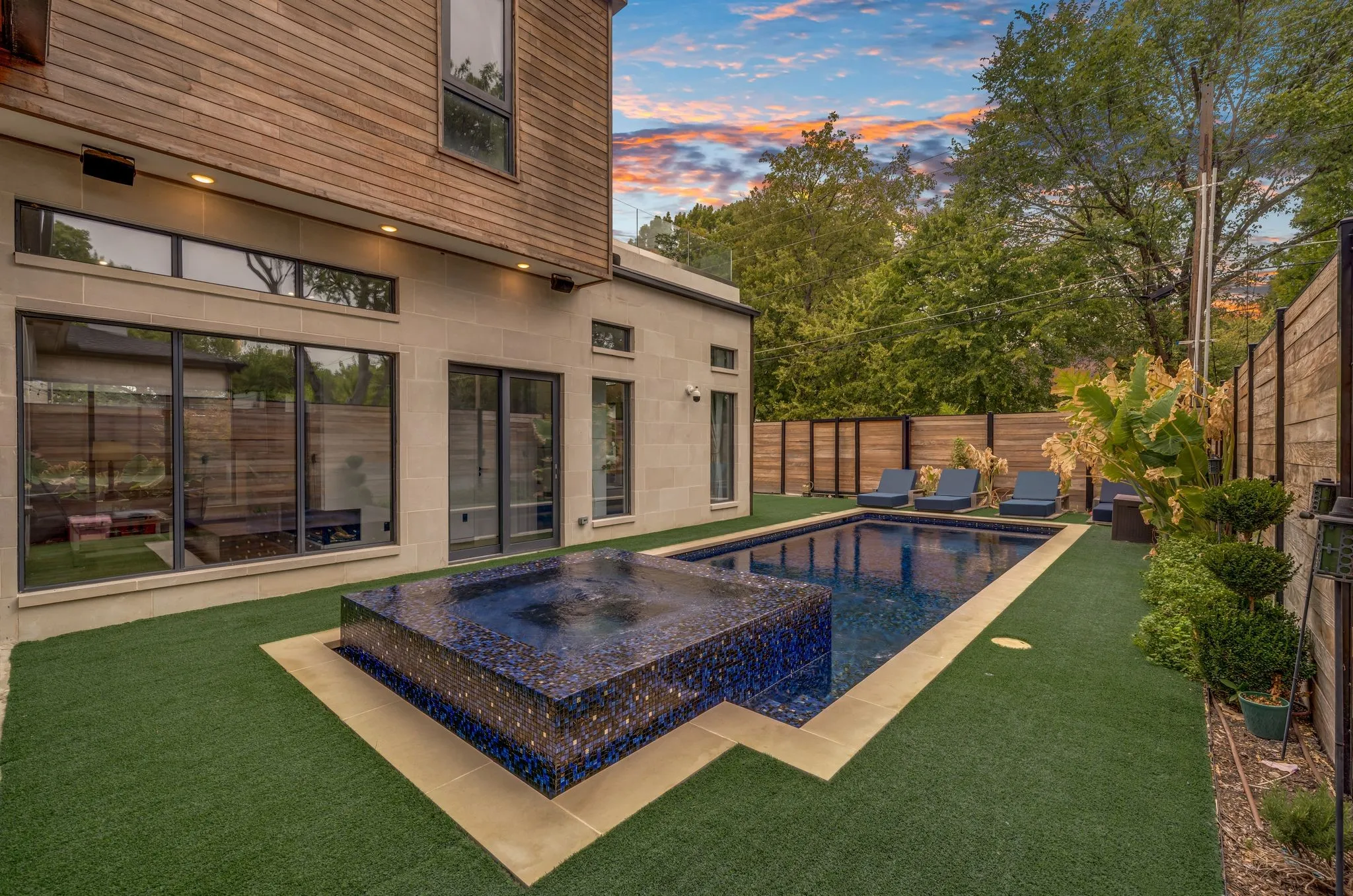 Exterior featuring a rectangular swimming pool, integrated spa, artificial turf, and wood-paneled privacy fencing