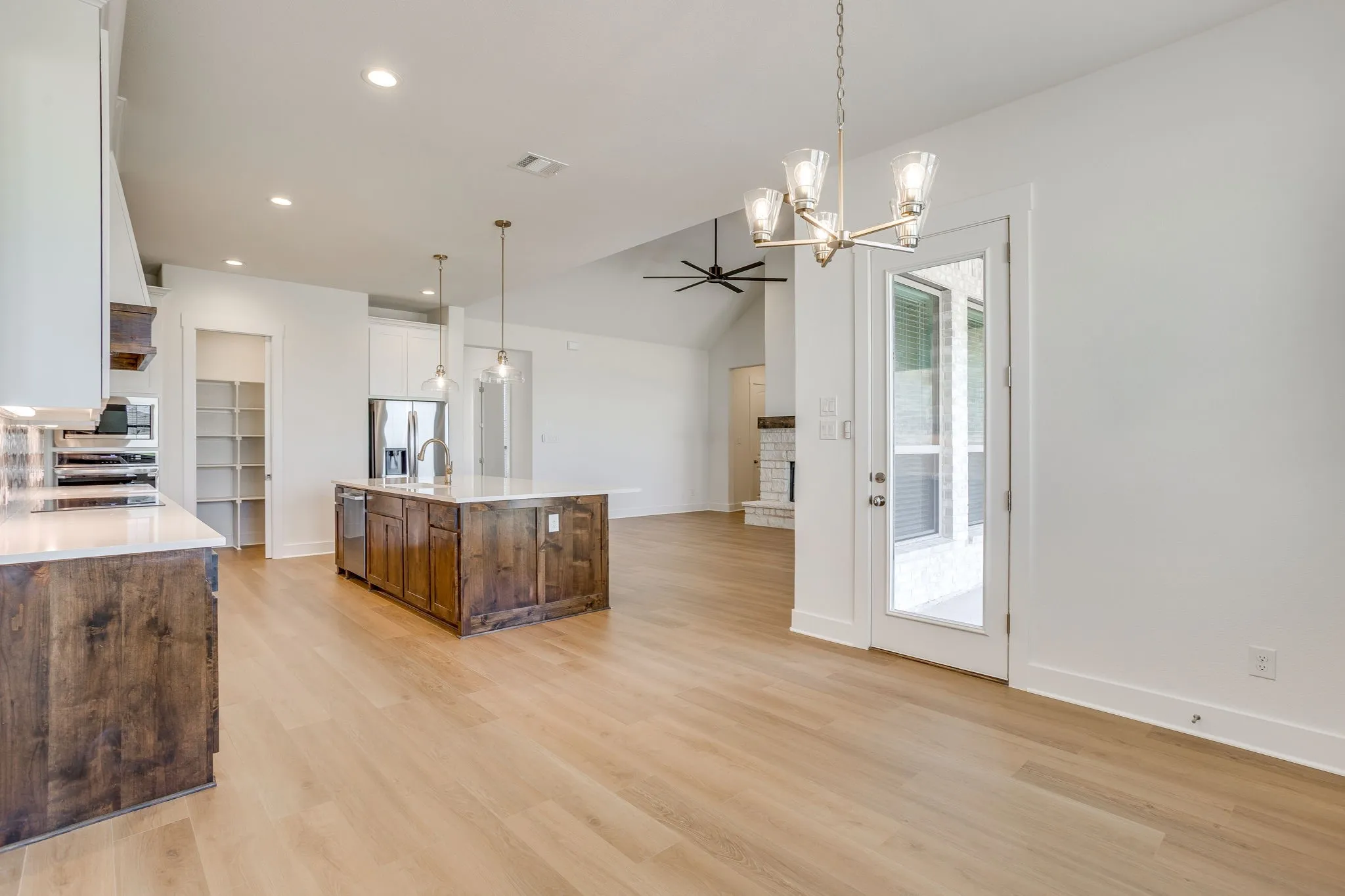 Open-concept living area featuring wood-finish flooring, a kitchen island with integrated sink, stainless steel appliances, and recessed lighting